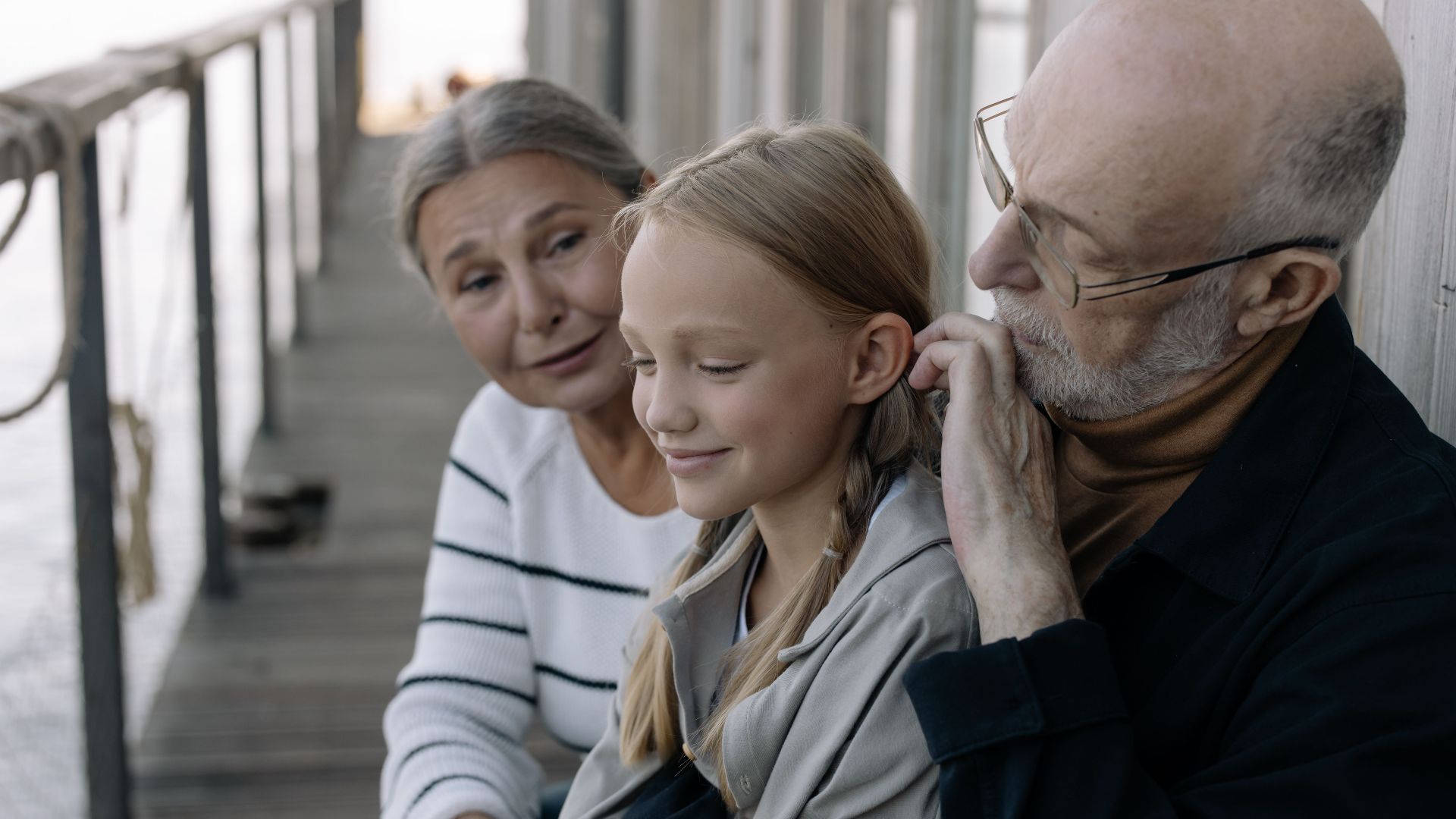 A heartwarming scene of grandparents sharing time with their granddaughter on a wooden deck.
