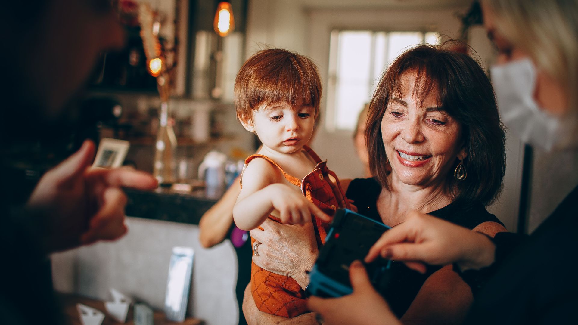 Heartwarming moment of a grandmother holding a child at a family gathering indoors.