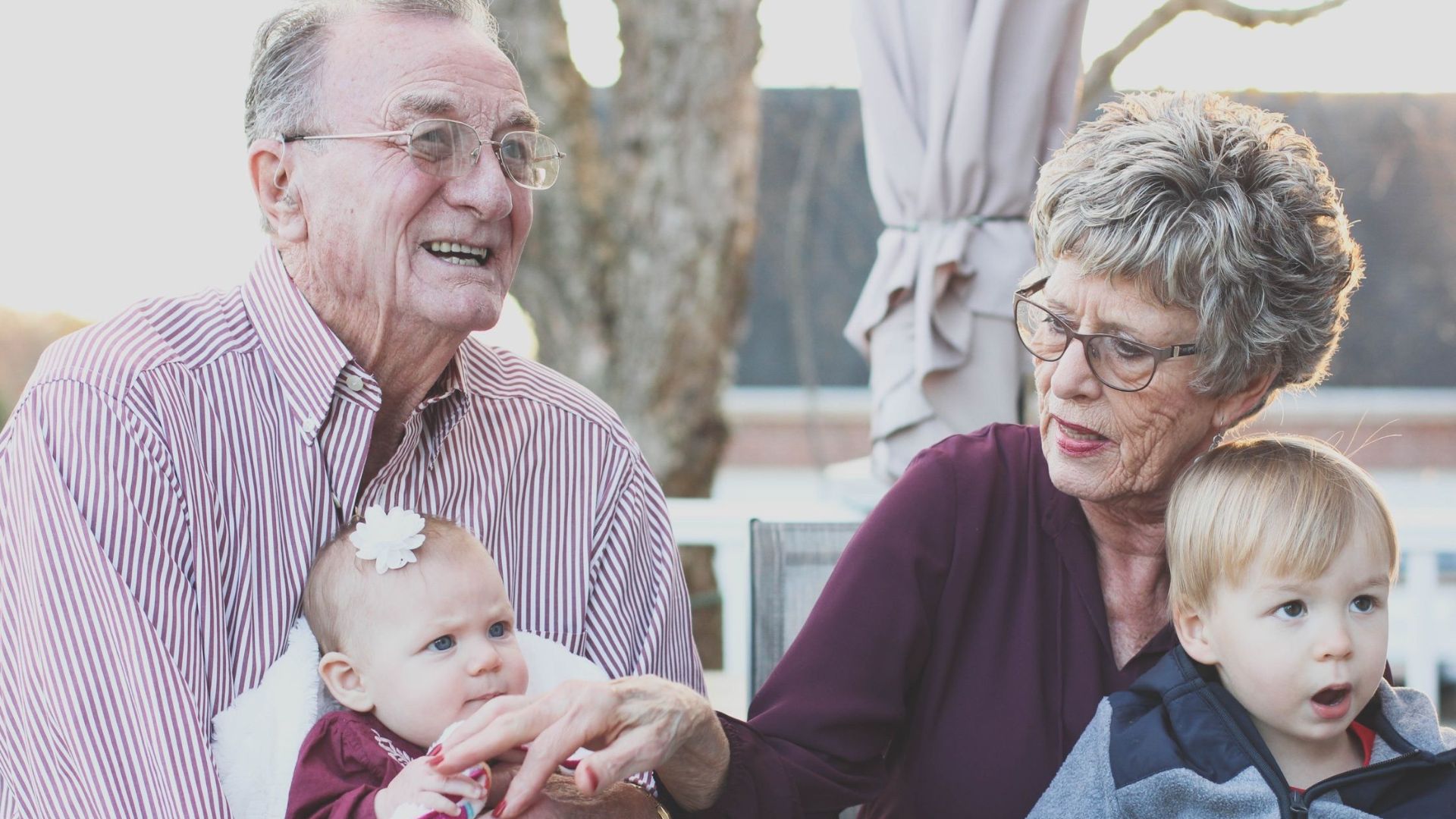 Grandparents spending joyful moments with their grandchildren in an outdoor setting, captured candidly.