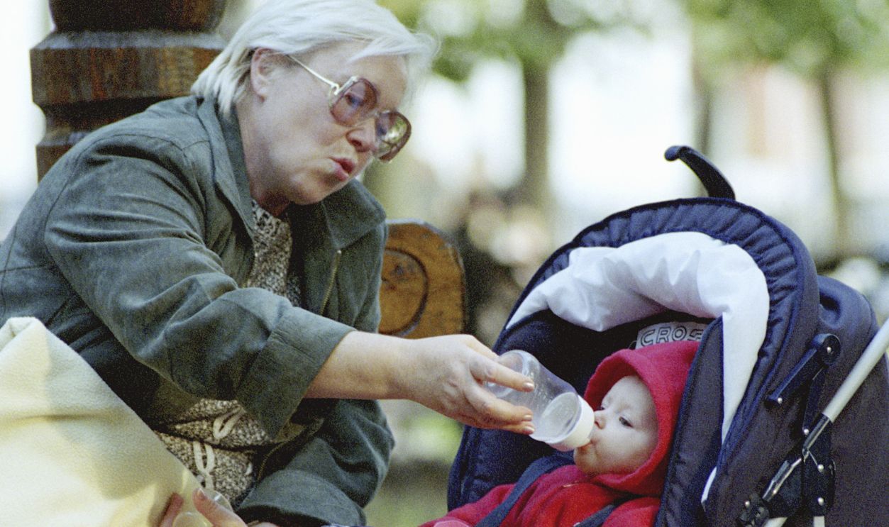 The grandmother feeds with milk of the grandson