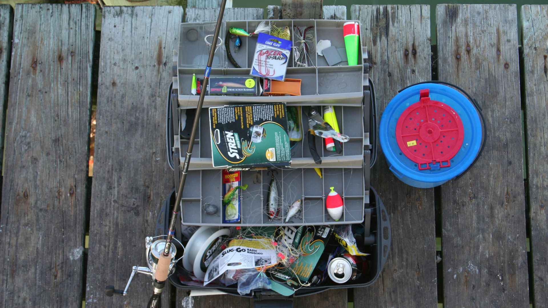 Typical tackle box with rod and fishing bait bucket.