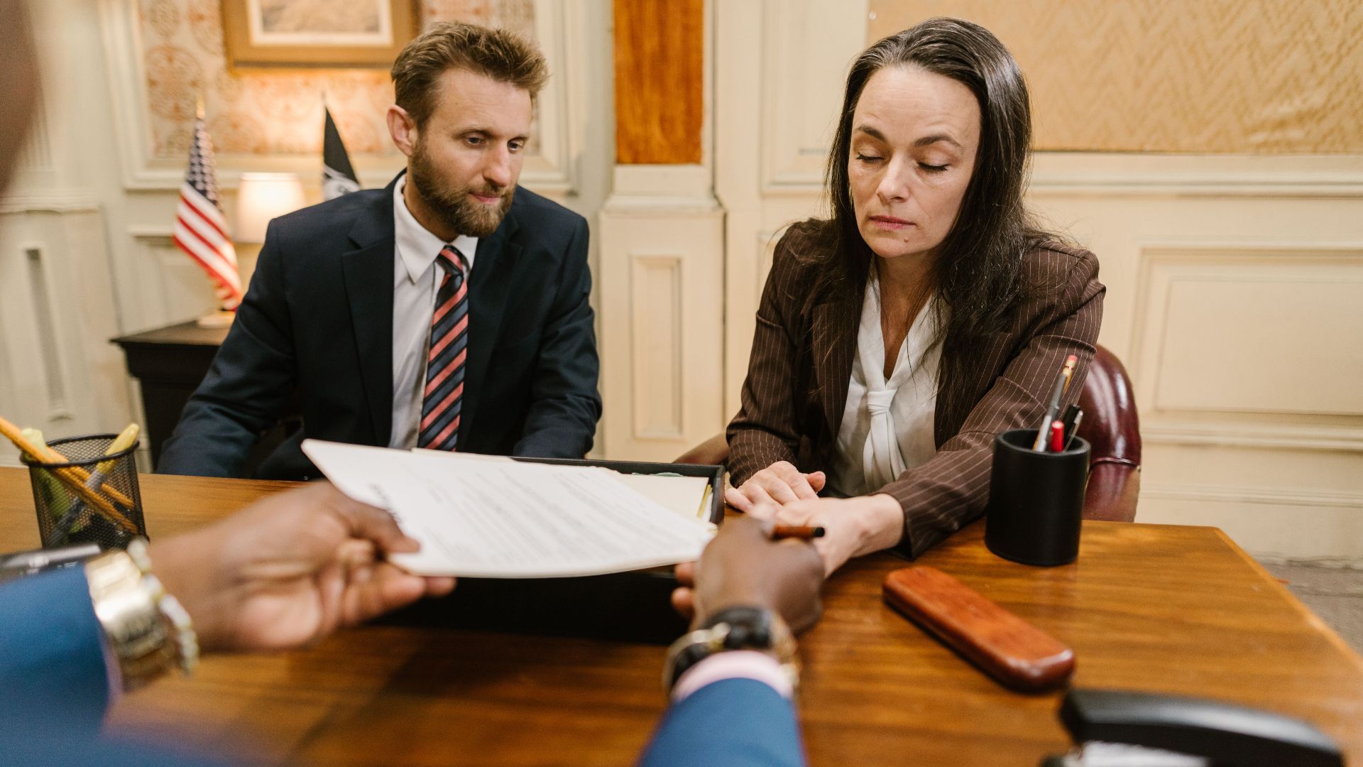 Professional business meeting with a woman and man discussing documents in an office setting.