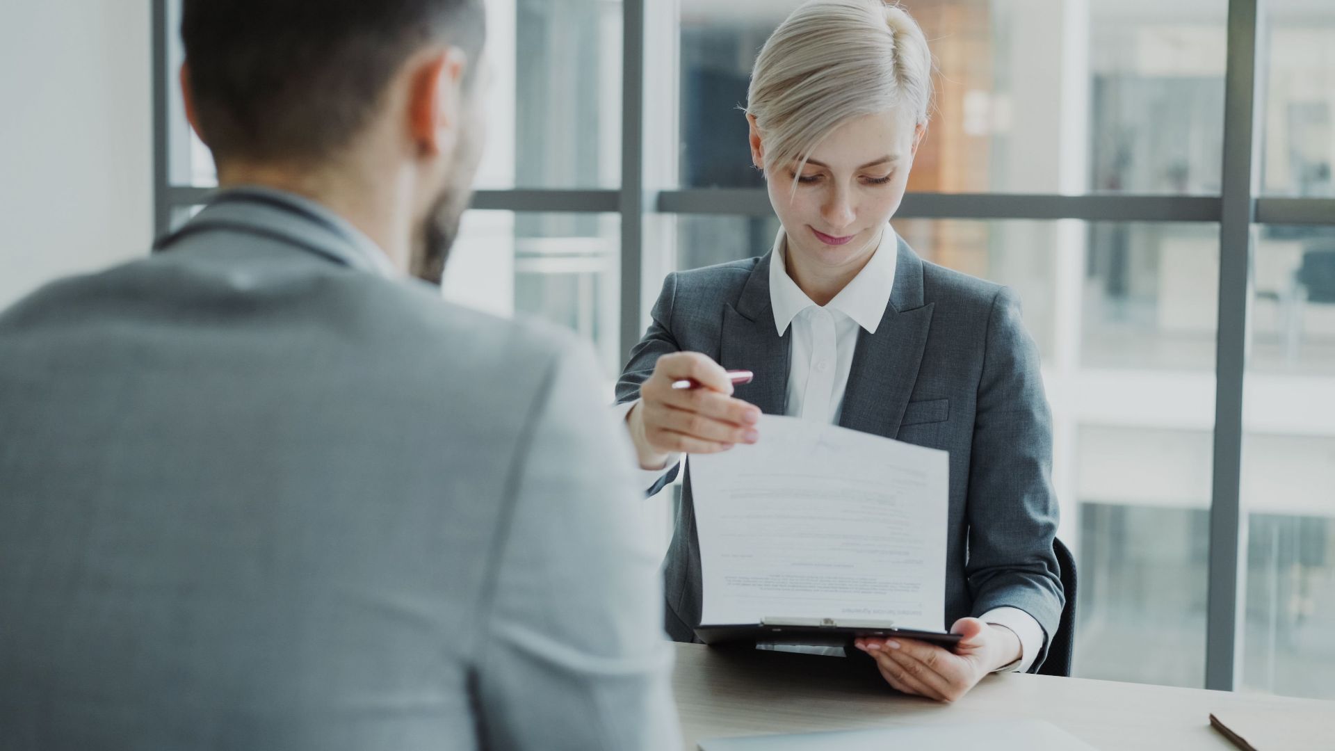 Business professionals reviewing a contract in a modern office setting.