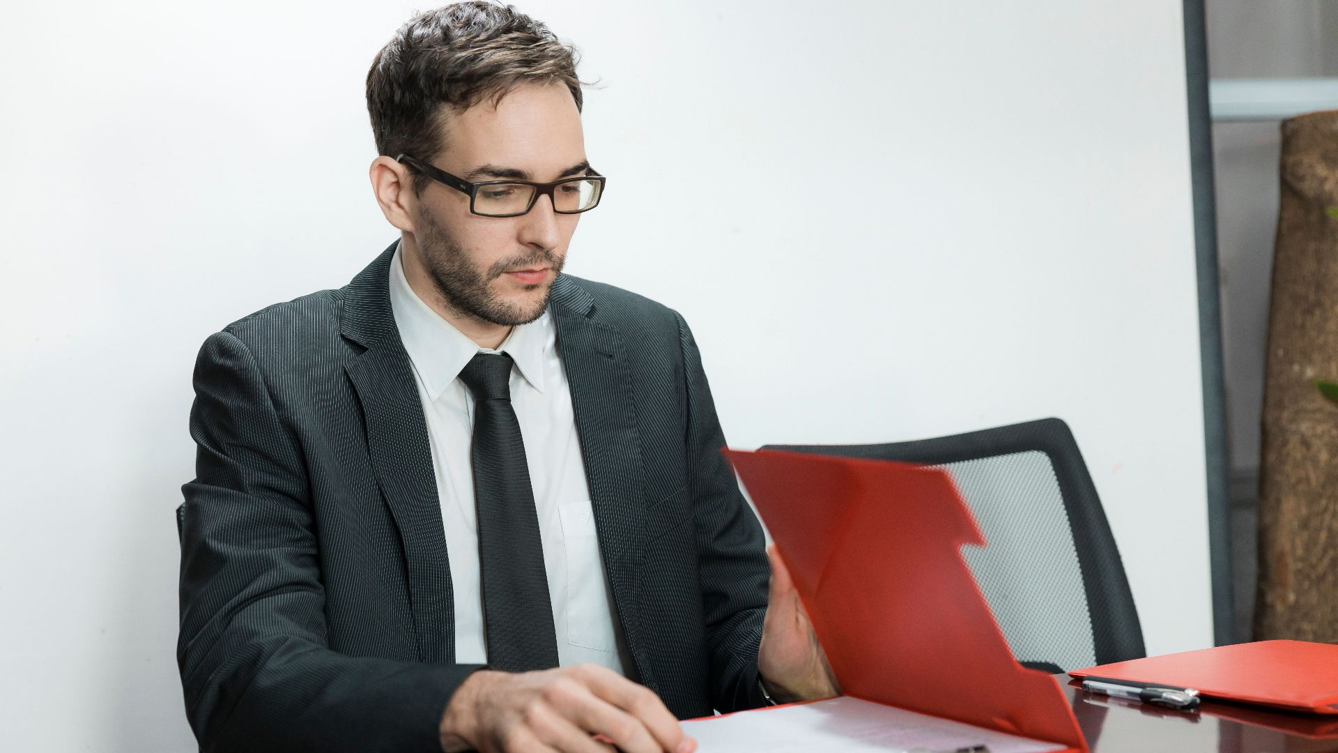 Professional man in suit reviewing papers at office desk with focus and determination.