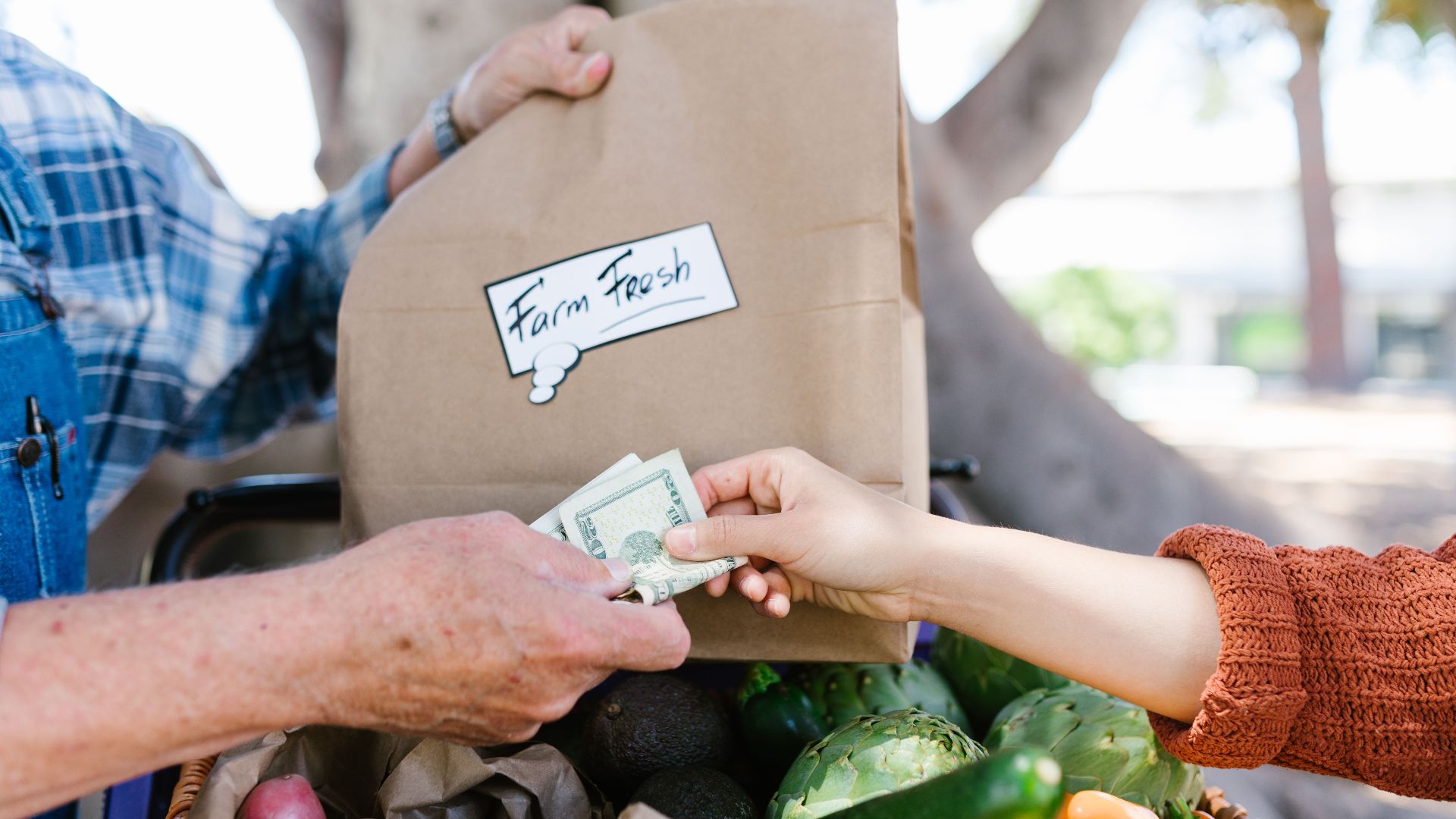 Close-up of a transaction at a farmer's market with fresh produce.