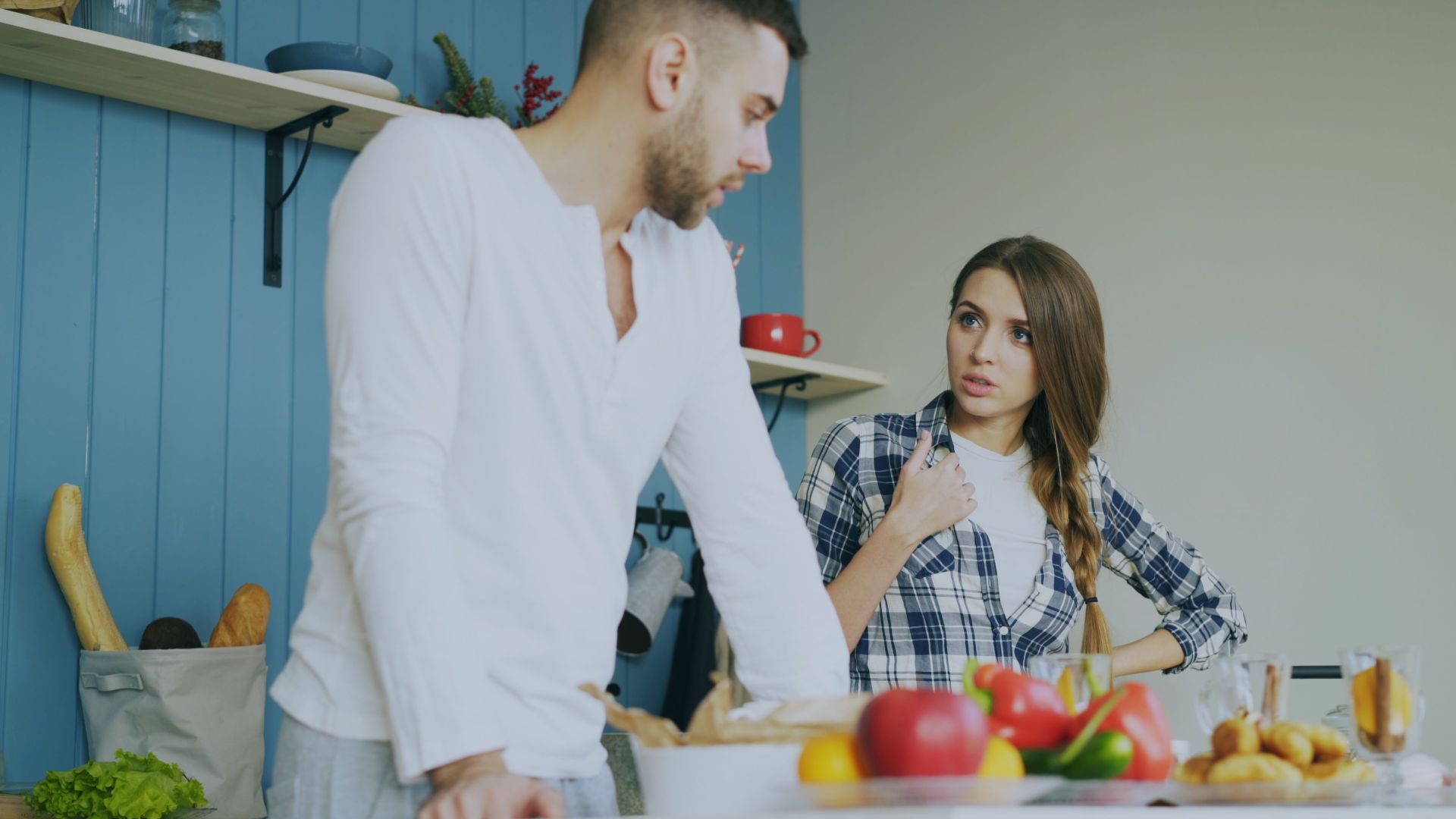 Young couple engaged in a conversation in a stylish kitchen with fresh fruits.