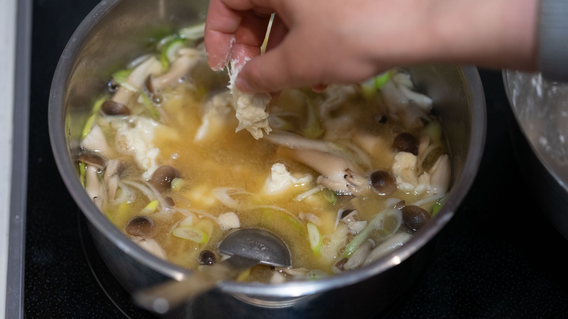 Preparing a flavorful Asian soup with fresh mushrooms and vegetables in a kitchen setting.
