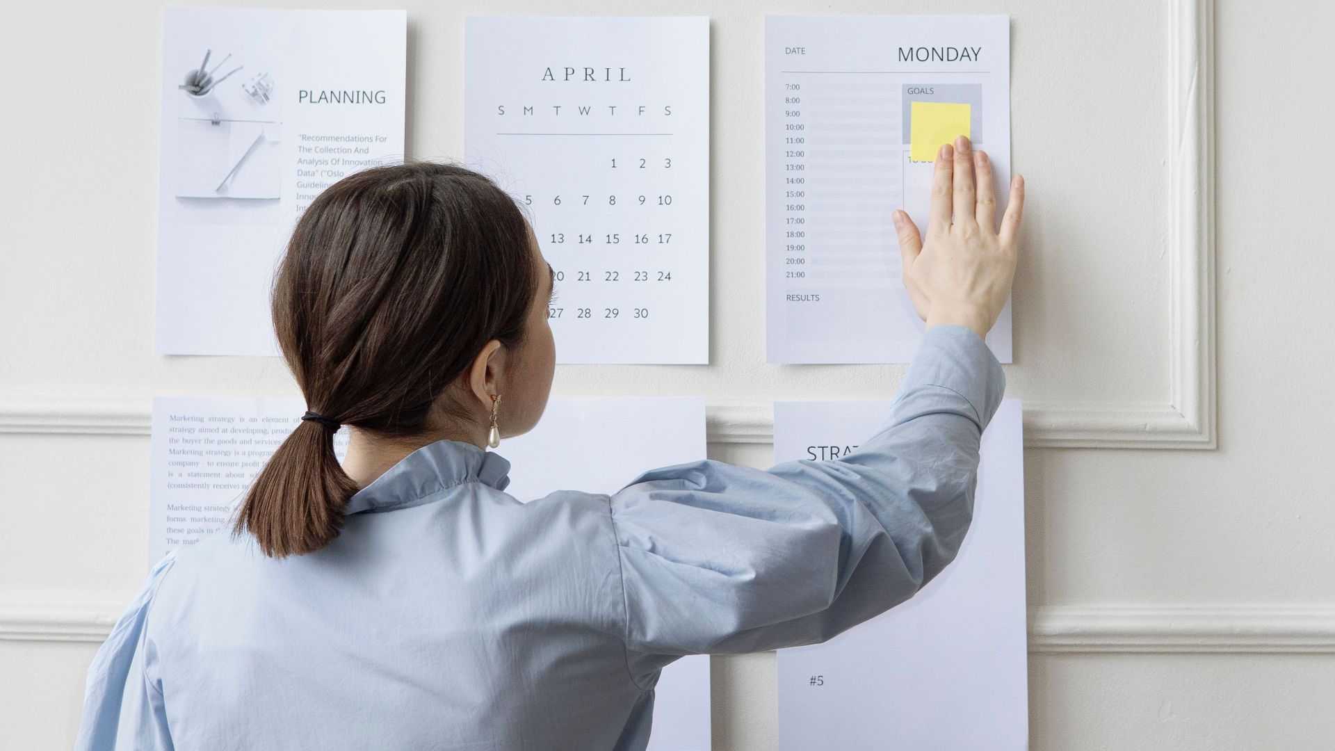 Woman organizing wall planner in office showing strategy and planning.