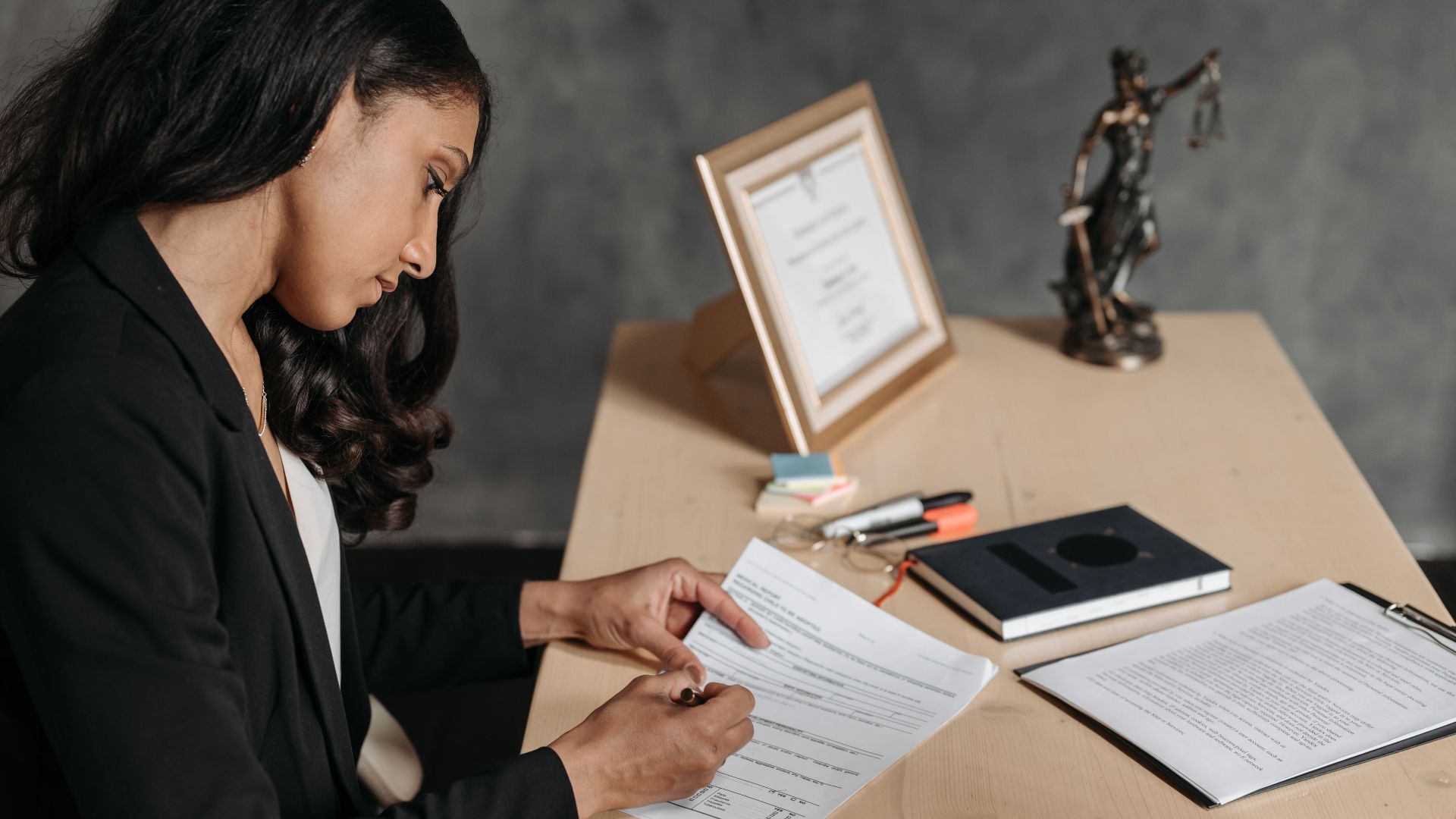 A lawyer or businesswoman reviews paperwork in an office setting.