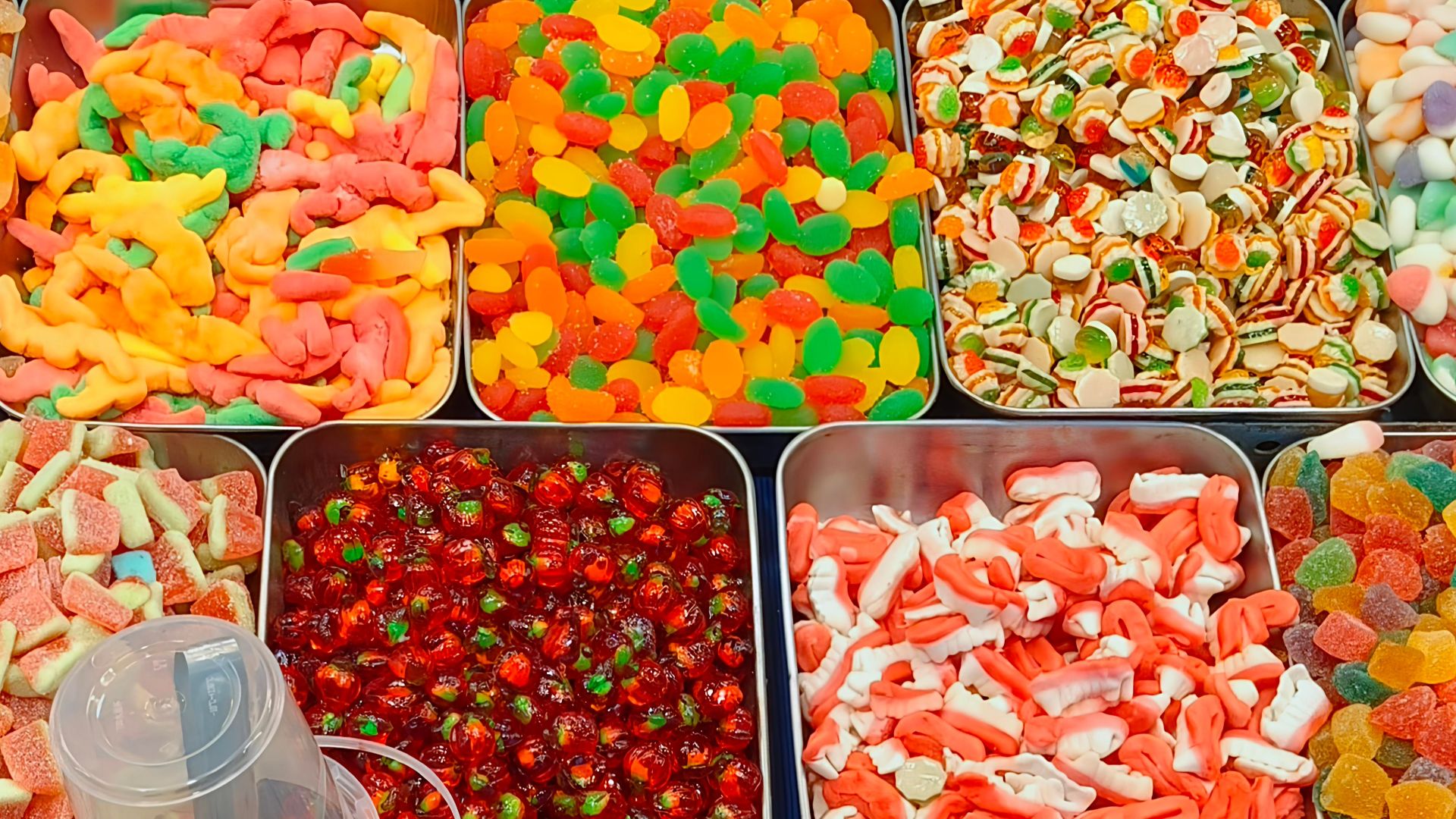 Vibrant assortments of colorful candies presented in metal trays for sale.