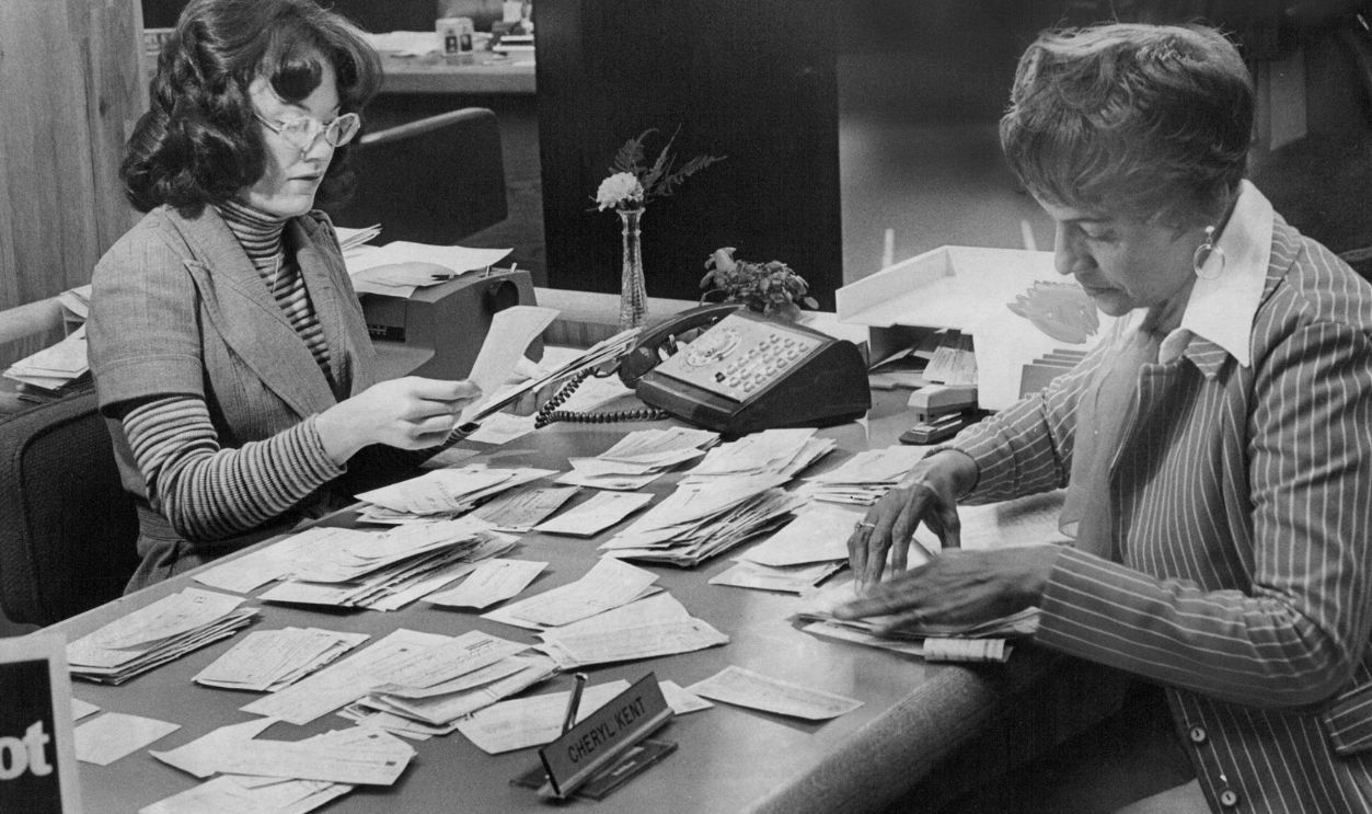 DEC 31 1976, JAN 1 1977; Cheryle Kent, Right, And Ruby Peterson Tally Checks Received In Fund Drive; They are receptionist-clerks at Central Bank of Denver, which is receiving money to try to save CWC