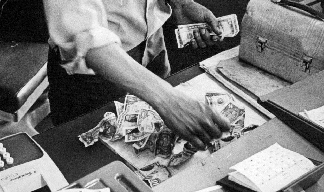 JUL 12 1969, JUL 13 1969; Foils Robber; Frank Lobato, 3800 W. Alameda Ave., operator of Frank's Par Service gas station at 4100 E. Colfax Avs., counts the approximately $70 he told police he recovered from a young man who tapped the station's till Saturday afternoon. Lobato said he recovered the money after he pursued the robber and shot him with a .32-caliber pistol, foreground. The robber fell, scattering the money, and Lobato went to call police. When they returned with him to area behind station, the wounded robber had