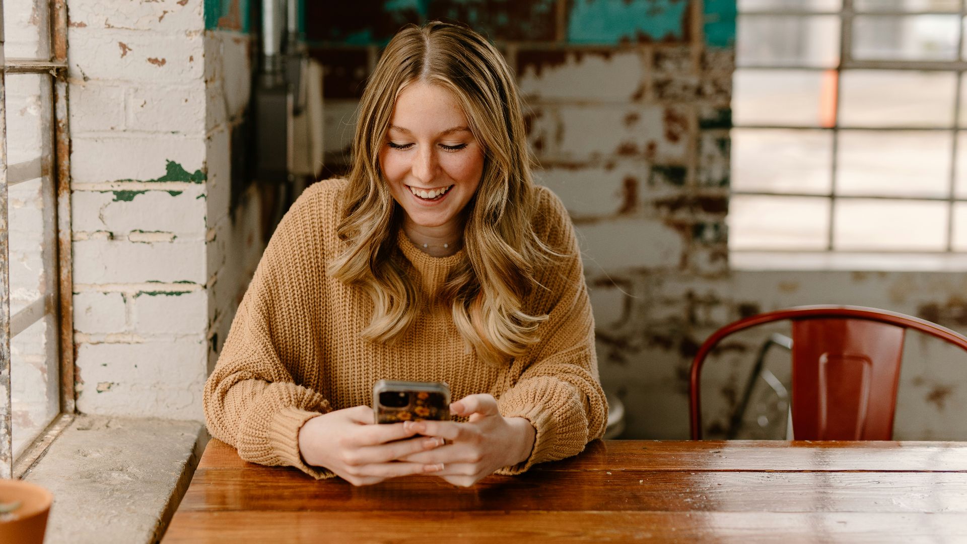 a woman sitting at a table looking at her cell phone