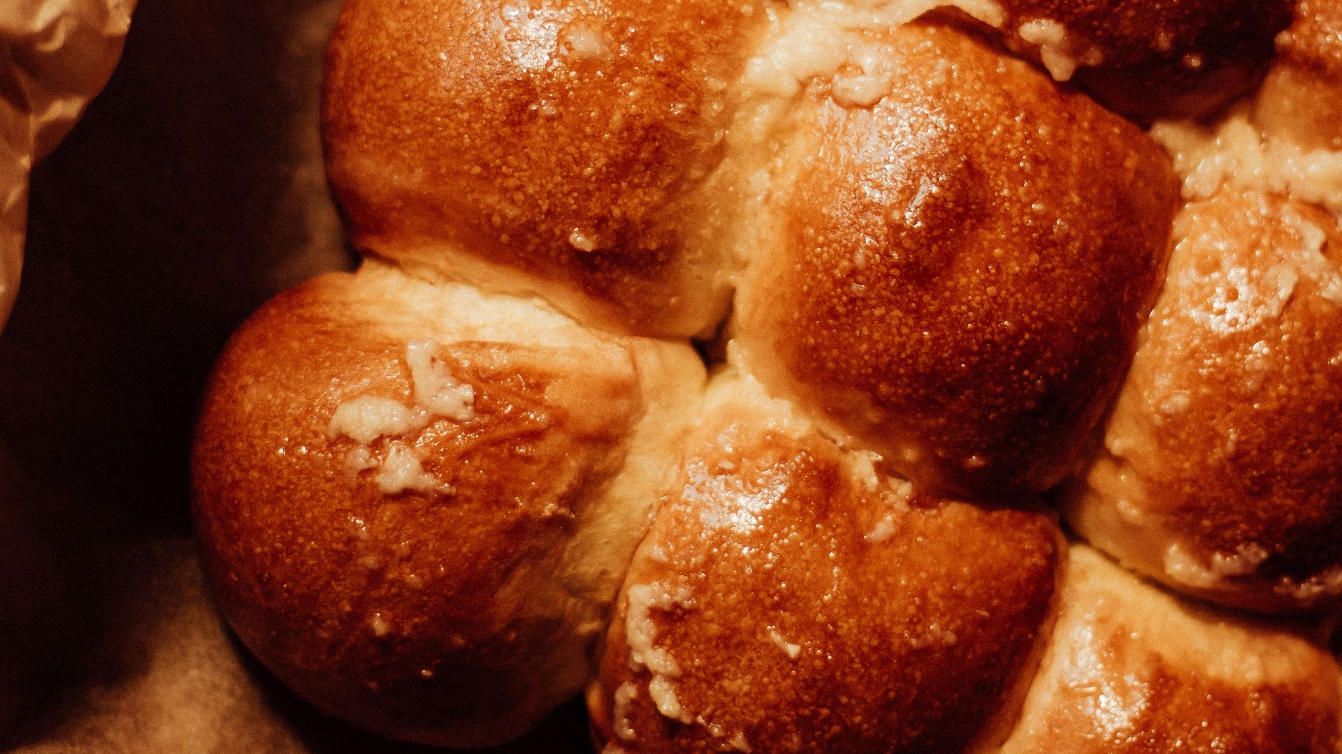 Close-up of freshly baked bread rolls with a golden brown crust on parchment paper, showcasing homemade craftsmanship.