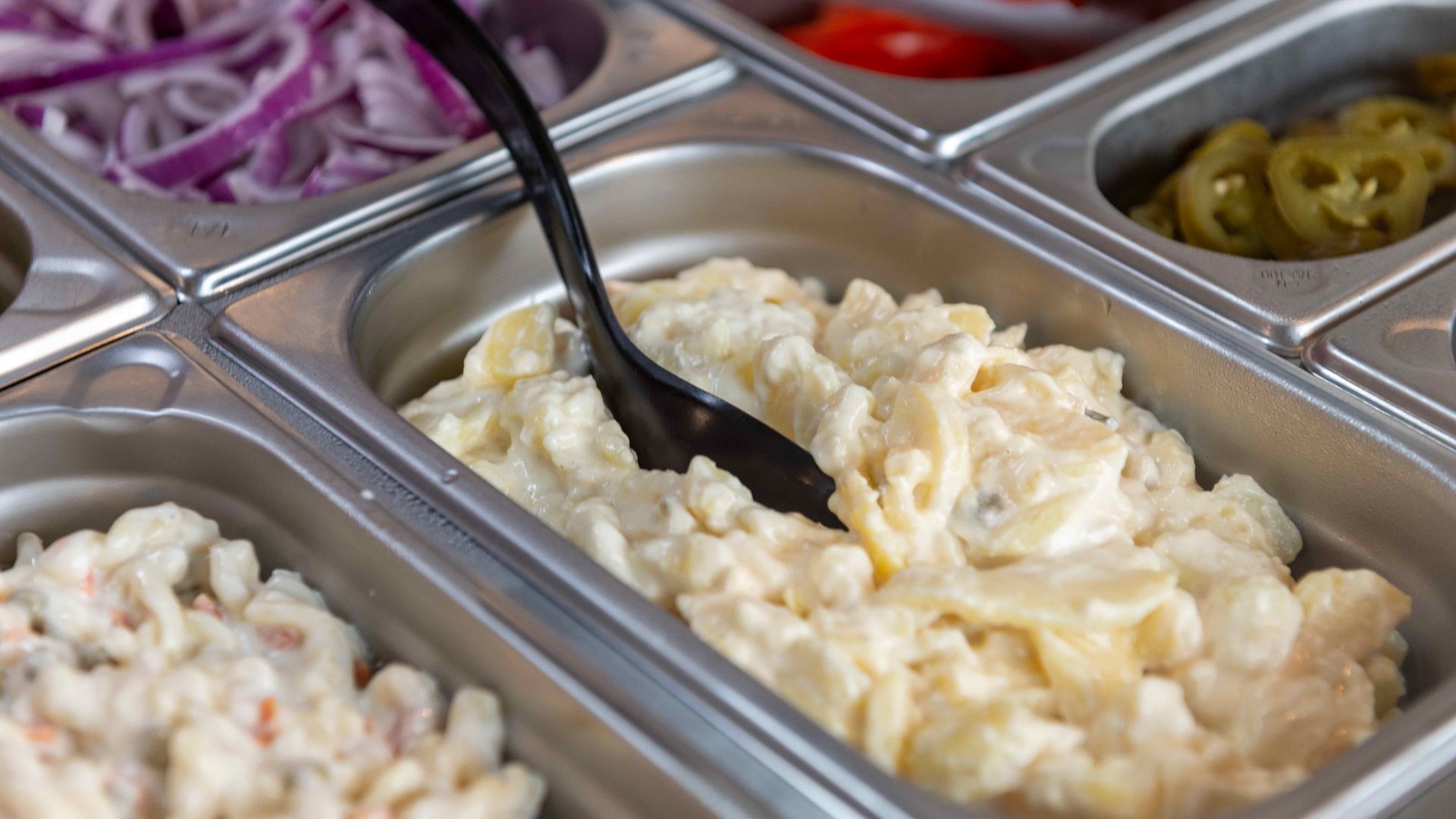 Delicious creamy potato salad ready to serve in a buffet setting. Perfect for lunch or dinner.