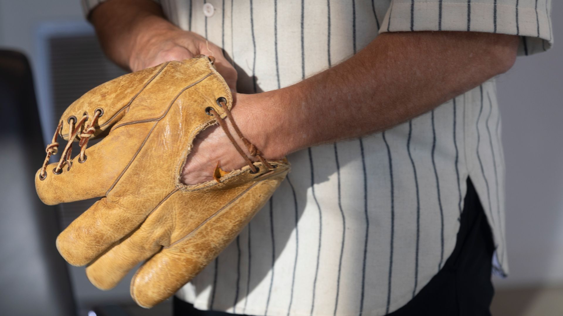 Dwier Brown, wearing a pinstriped shirt, holding a vintage leather baseball glove.