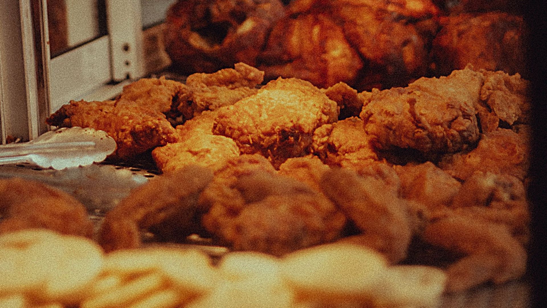A tempting array of golden fried chicken pieces displayed under warm lights at a local eatery in Mexicali.