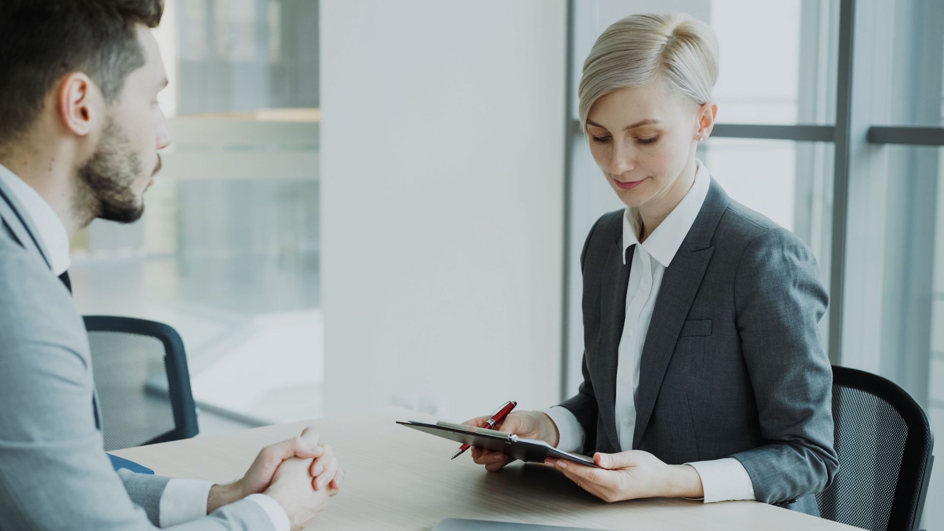 Two professionals in a modern office discussing business. Bright, professional setting.