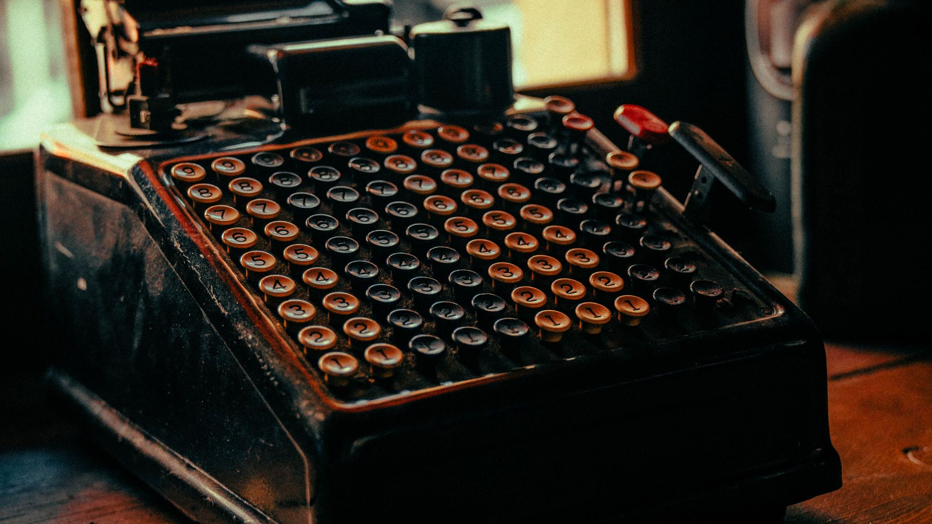 A close-up view of a retro adding machine with numeric keys in a warm, nostalgic setting.