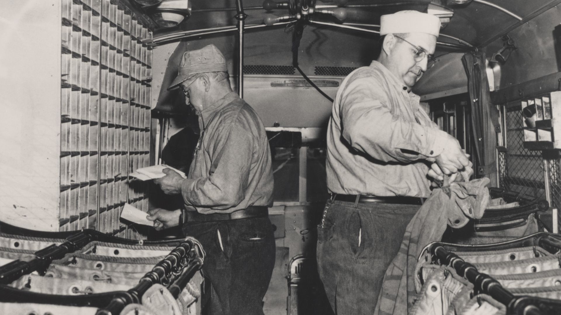 Description: Two Highway Post Office clerks sort mail inside the first Highway Post Office bus.
Creator/Photographer: Unidentified photographer
Medium: Black and white photographic print
Geography: USA
Date: 1941
Collection: U.S. Postal Employees
Reposito