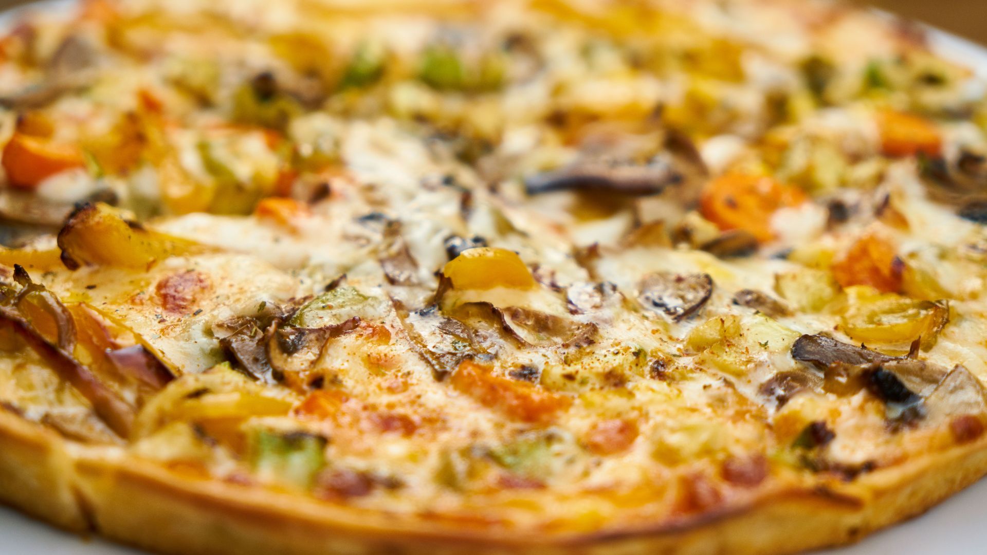 Mouth-watering close-up of a freshly baked veggie pizza with mushrooms and bell peppers.