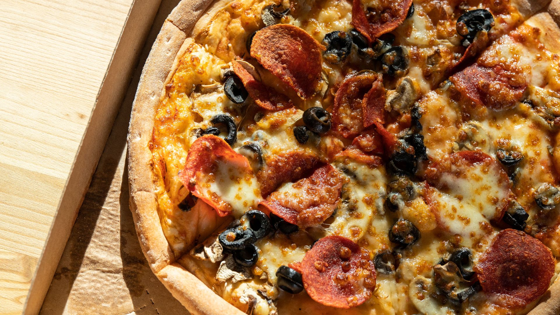 Delicious pepperoni and olive pizza in an open box, mouthwatering and savory.