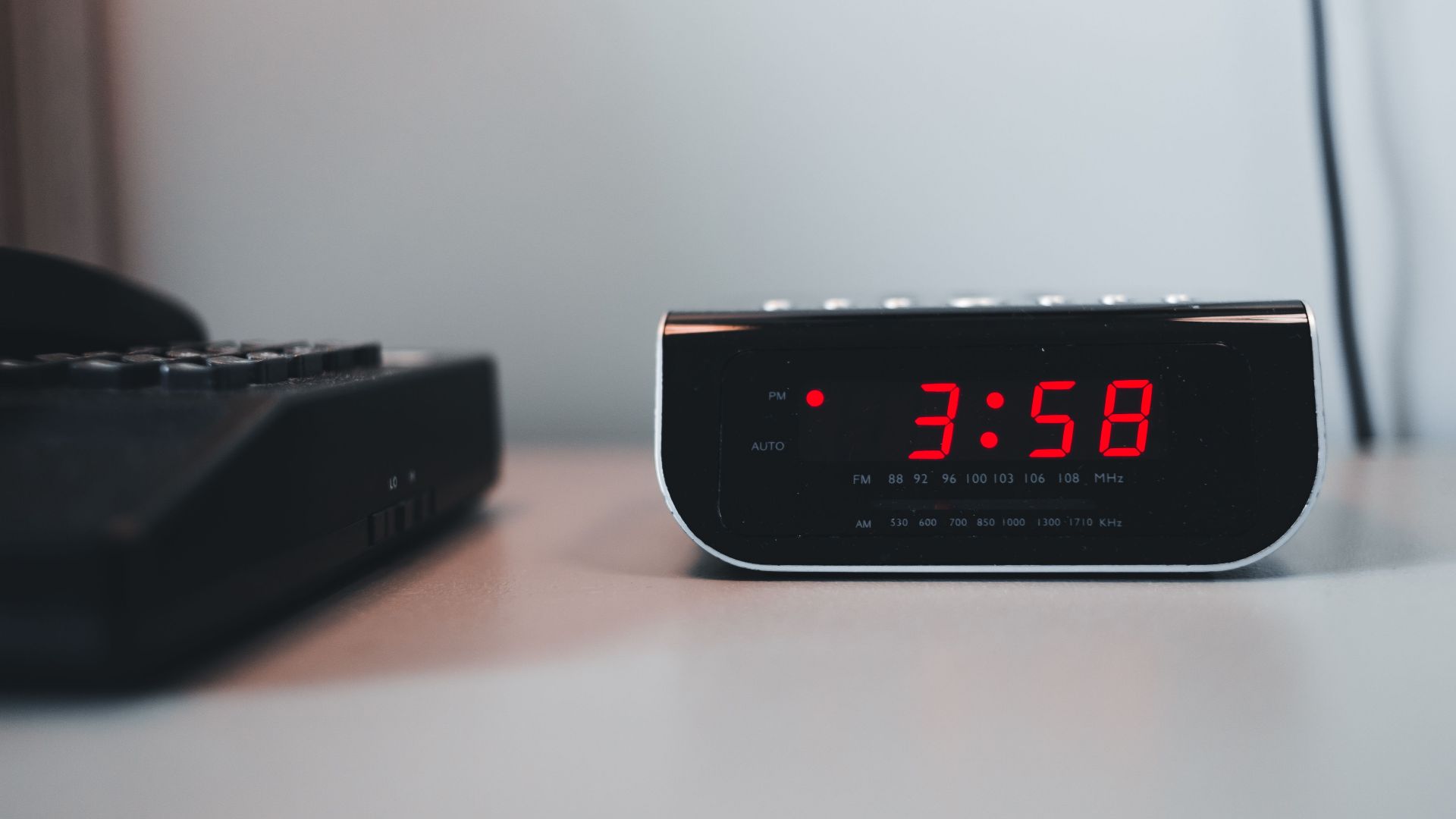 Close-up of a digital alarm clock displaying 3:58 PM on a white surface, signifying technology and time.