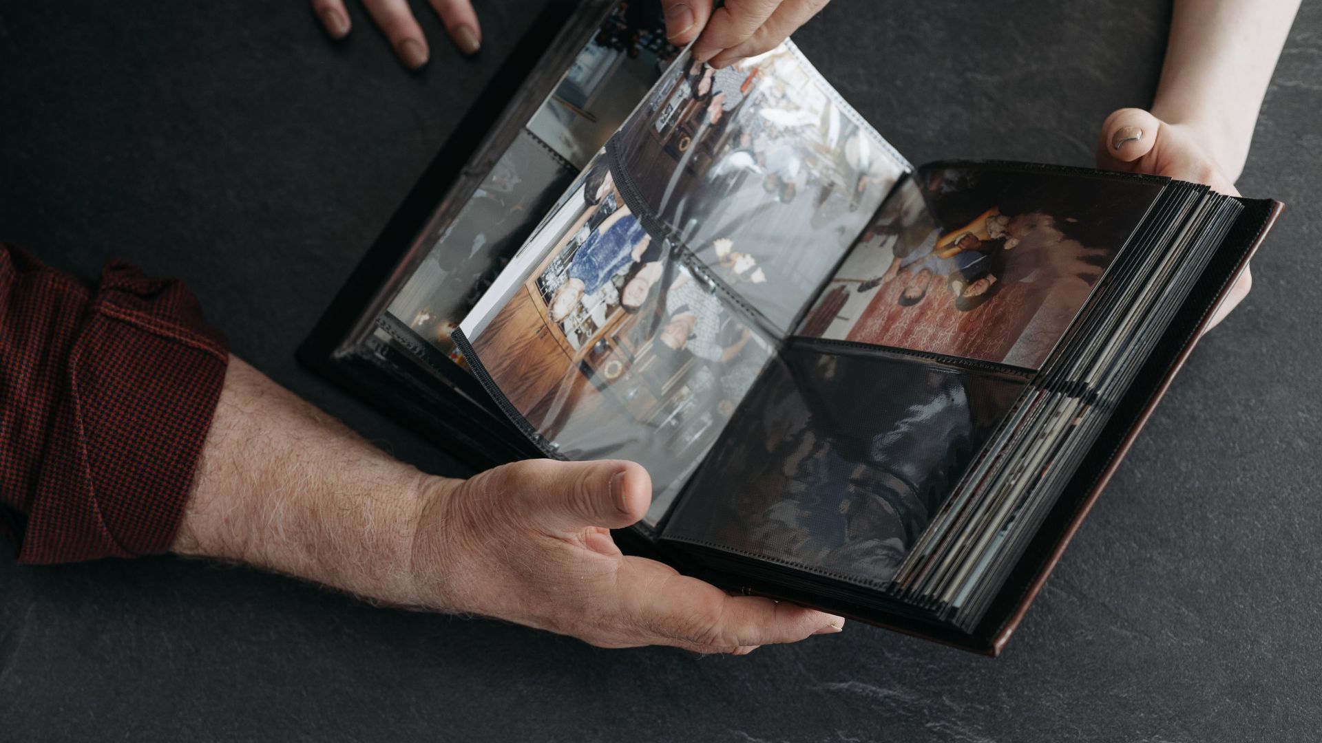 Hands holding a photo album with coffee cups, evoking memories and nostalgia.