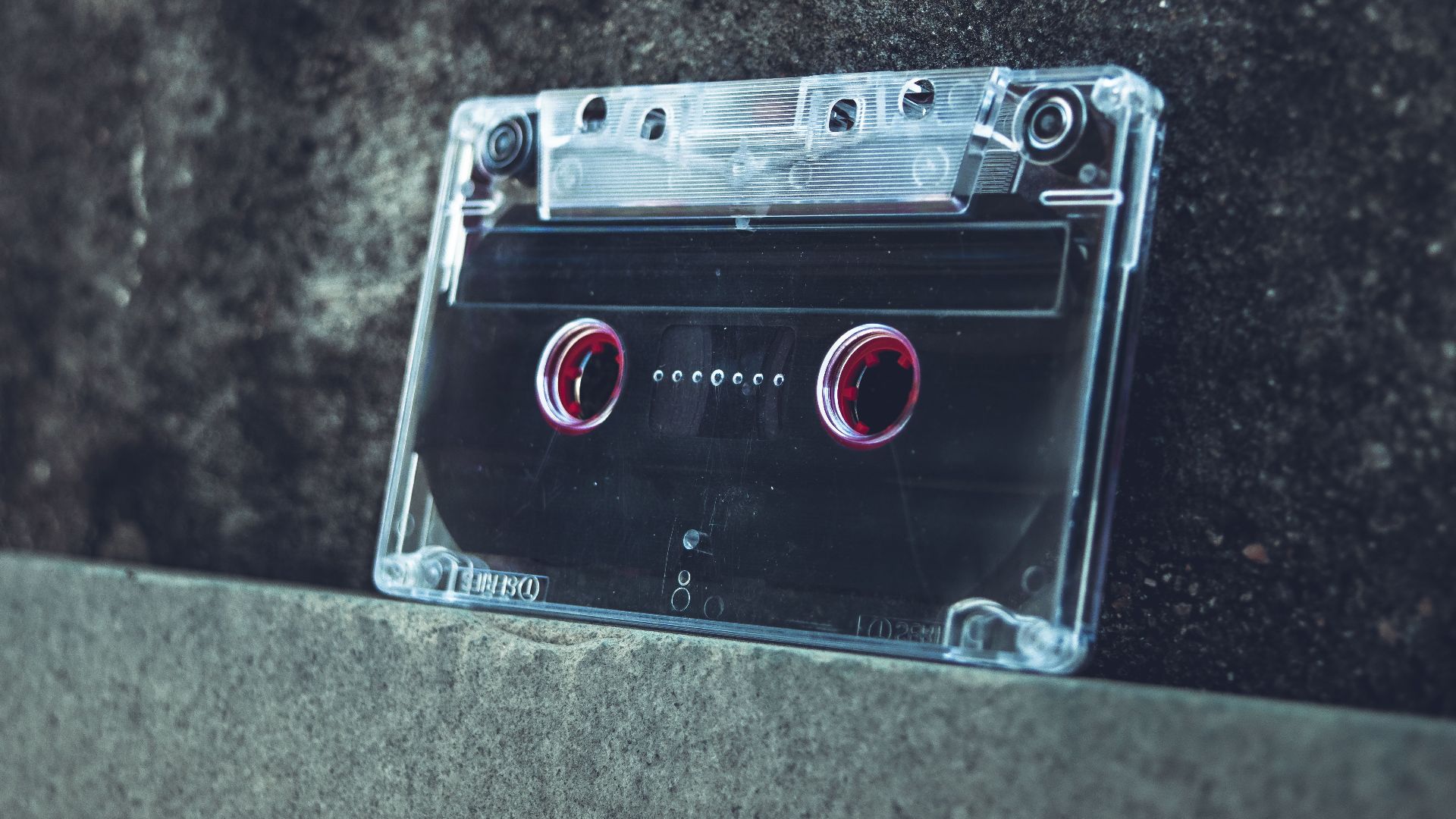 A clear cassette tape resting on a concrete surface evokes a vintage and nostalgic vibe.