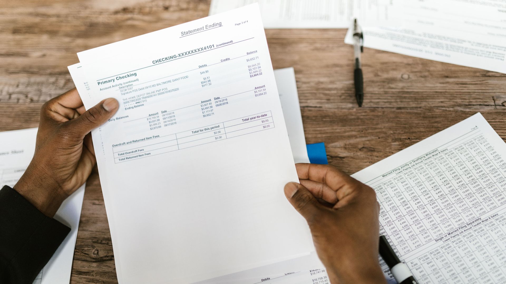 Hands holding financial papers for tax preparation and analysis.