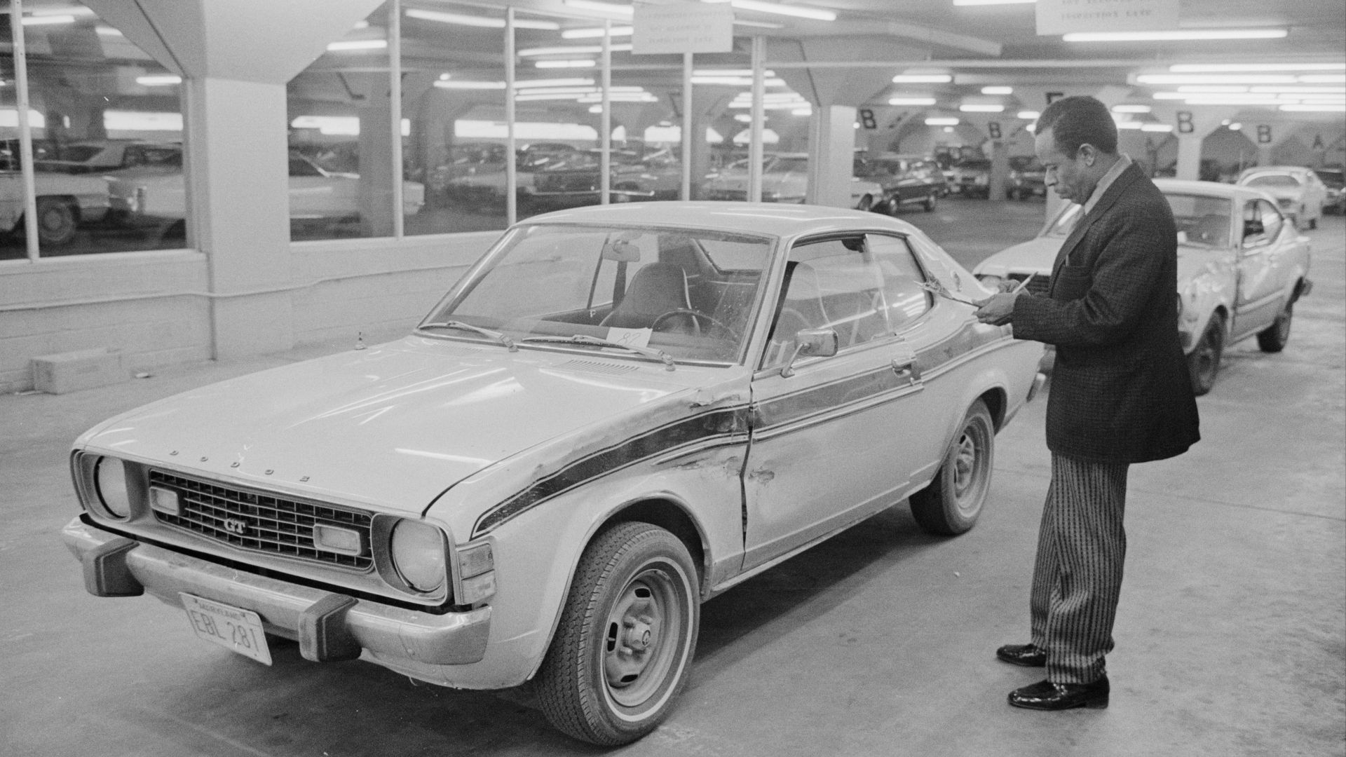 Man examining a damaged car at the Government Employees Insurance Company (GEICO) auto damage estimation lane