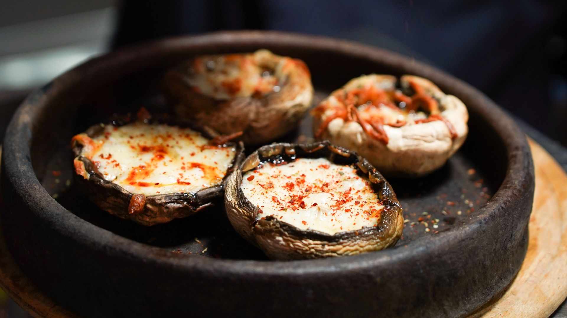 Close-up of a chef seasoning stuffed mushrooms in a Gökçeada taverna, capturing the essence of culinary artistry.