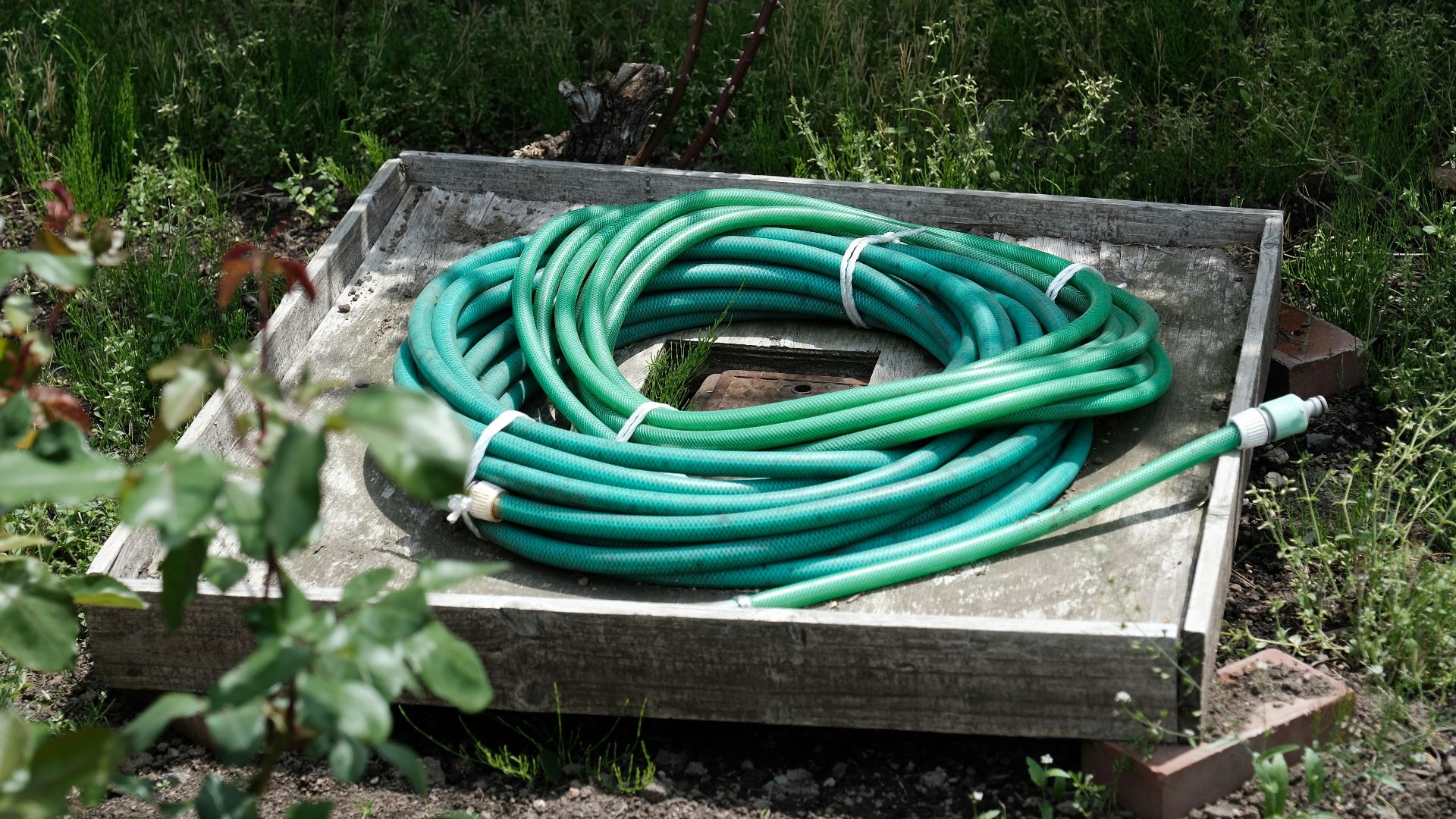 a bunch of green hoses sitting on top of a wooden box