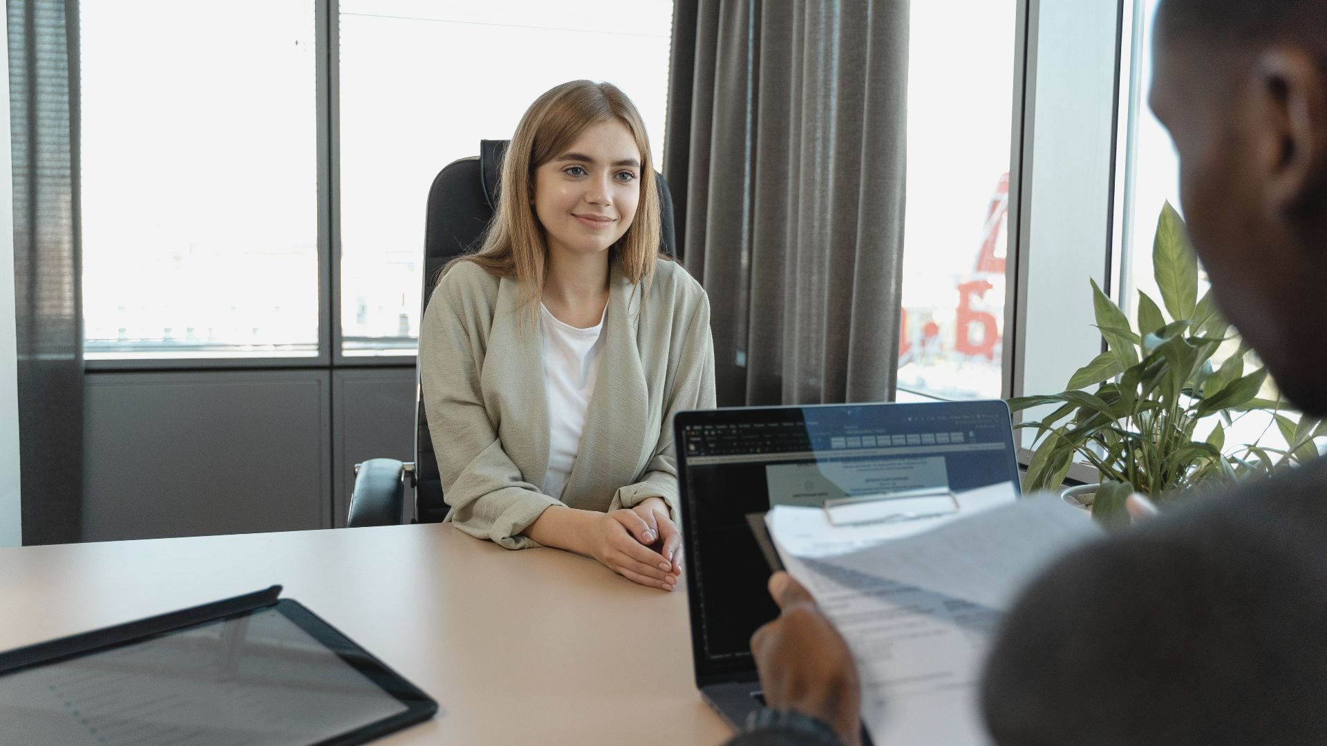 Young woman sitting confidently in a modern office for a job interview.