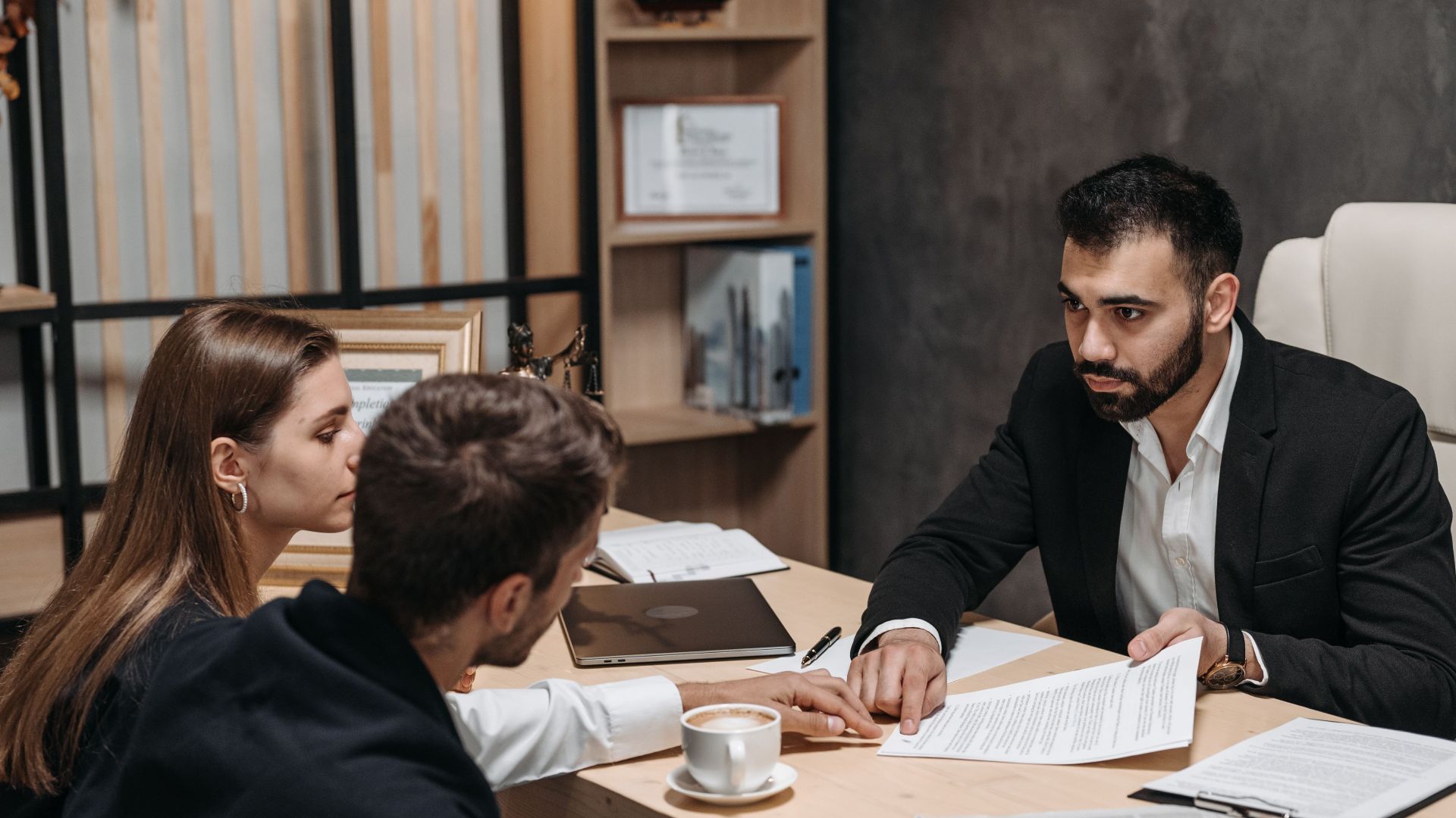 Lawyer discussing legal documents with clients at office desk.