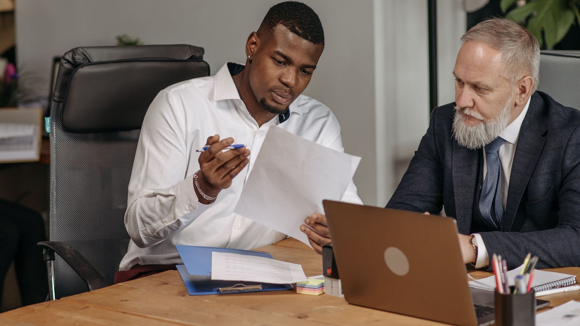 Business professionals discussing documents in a modern office environment with focus on teamwork and collaboration.