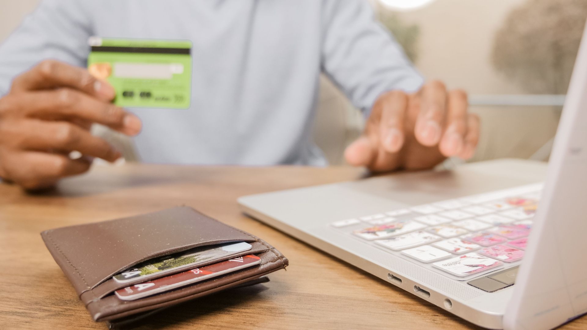 Close-up of hands with a bank card and laptop for online shopping. Perfect for illustrating e-commerce concepts.
