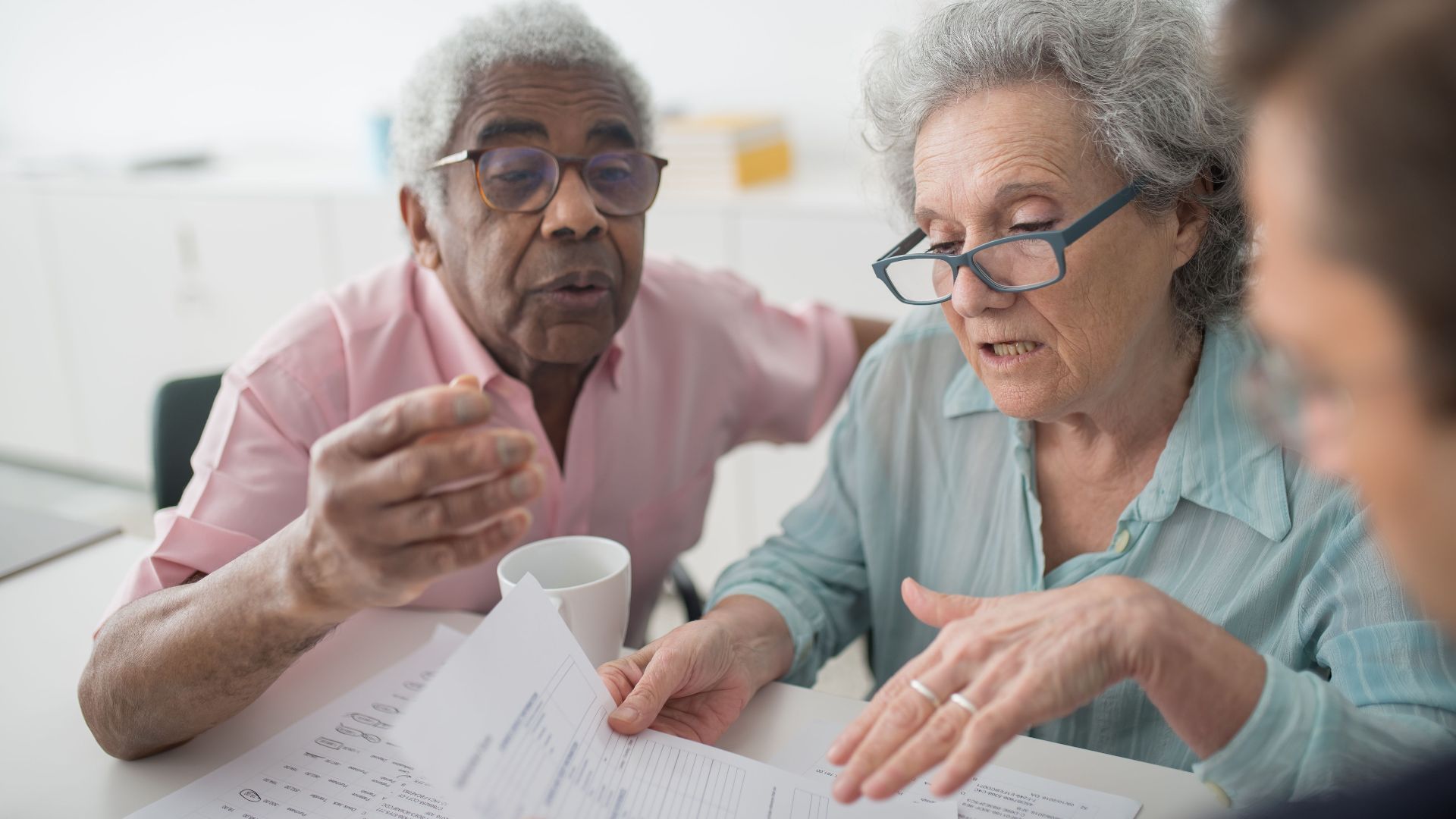 Elderly couple discussing financial documents with a consultant in an office setting.