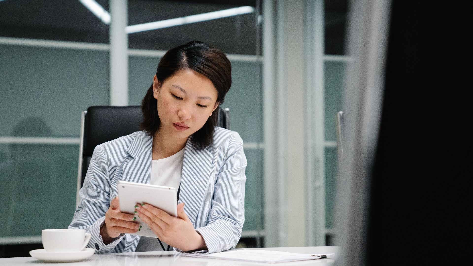 Professional businesswoman working on a tablet at a sleek office desk.