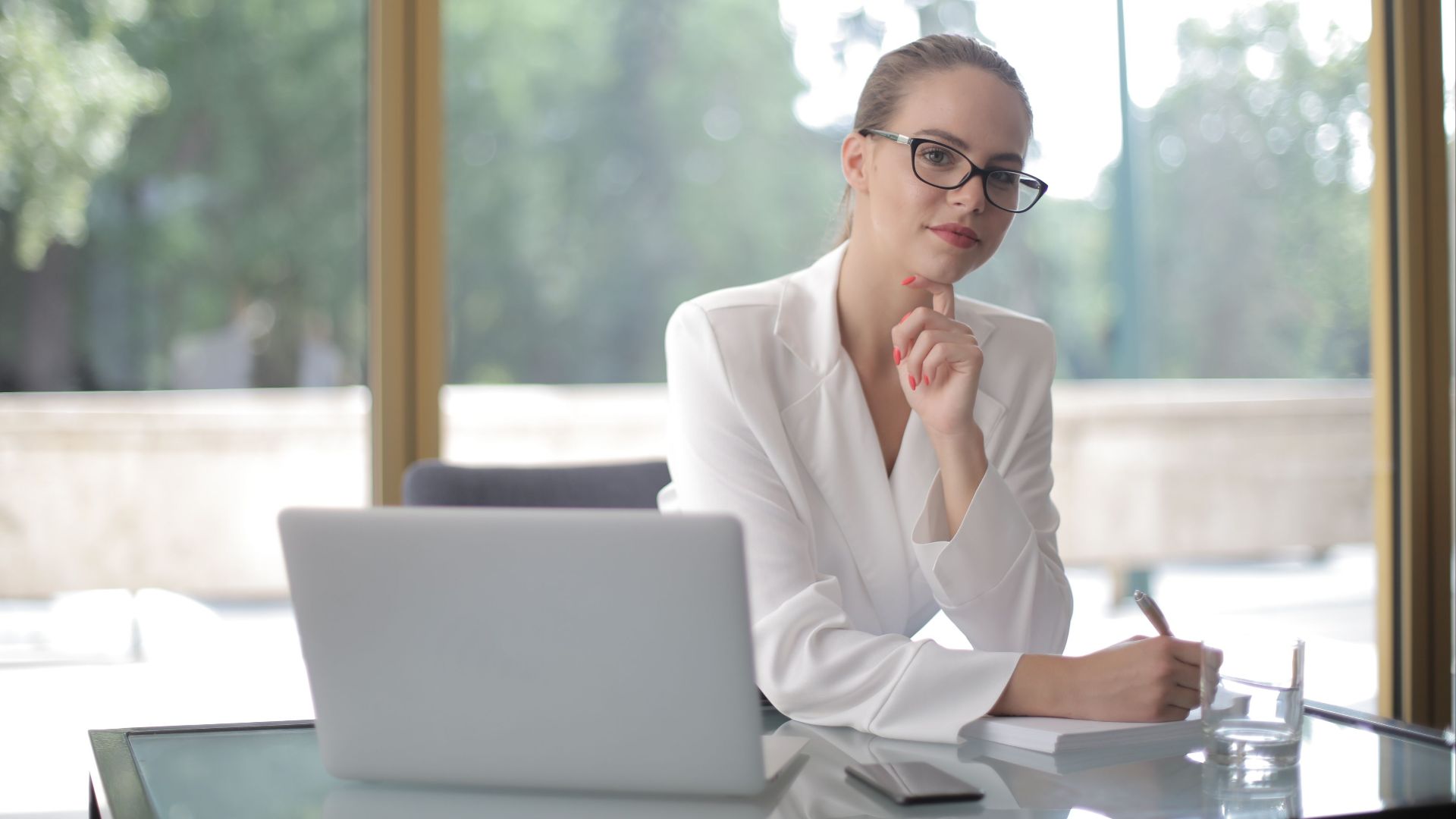 Confident woman in glasses working at a desk, embodying modern professionalism.