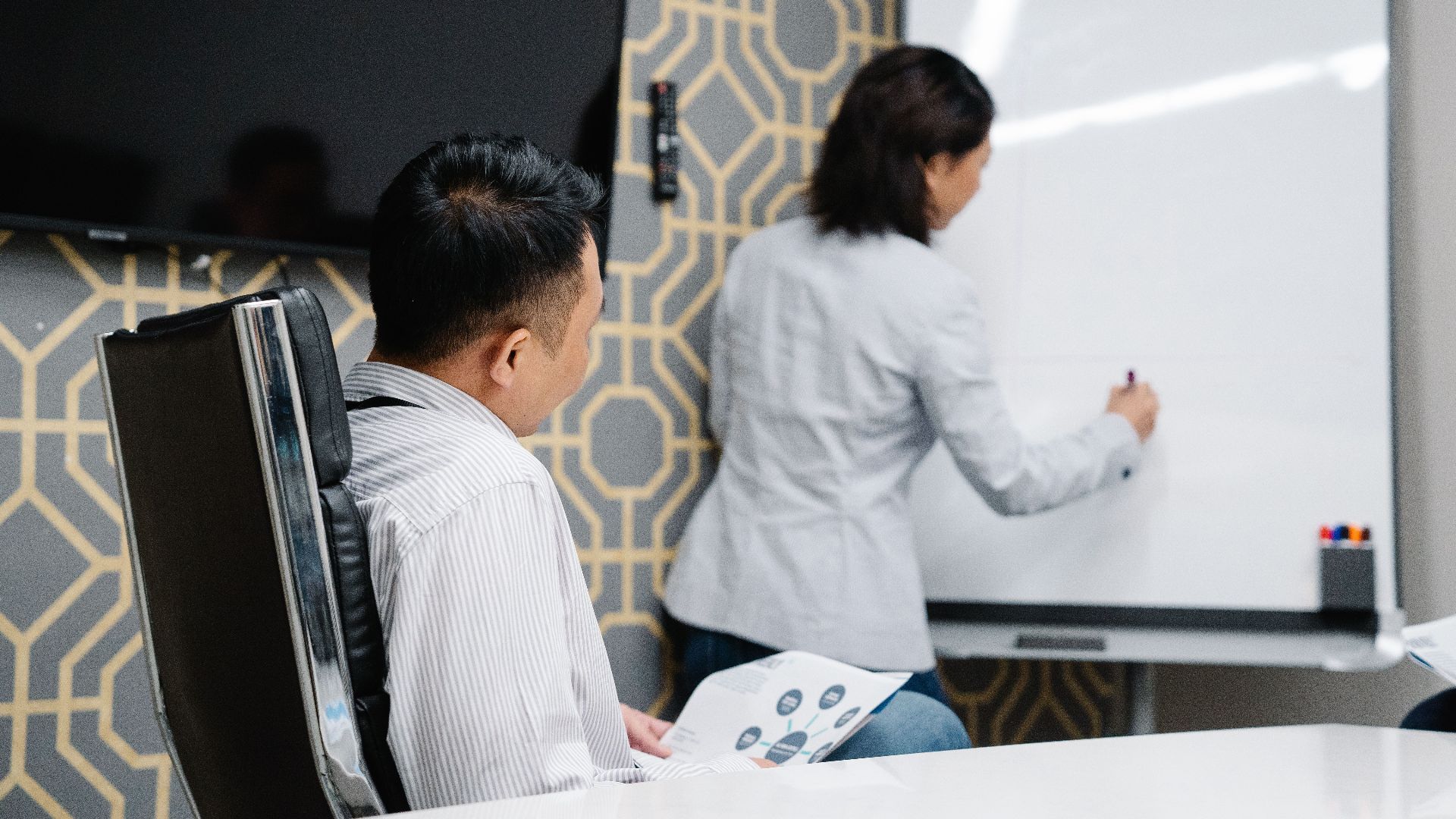 Business professionals engaging in a collaborative meeting using a whiteboard for brainstorming.