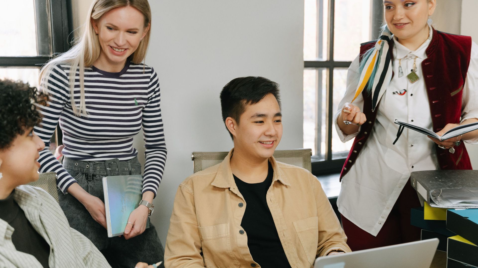 A diverse group of young professionals collaborating in a modern office setting, engaging in teamwork and discussion.