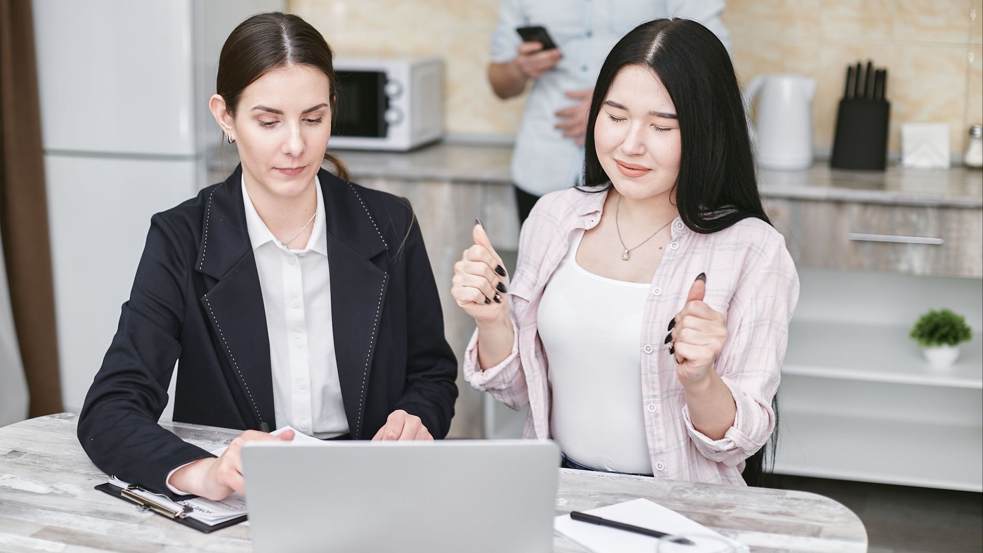 Two women collaborating on a laptop in a modern office space, focusing on teamwork.