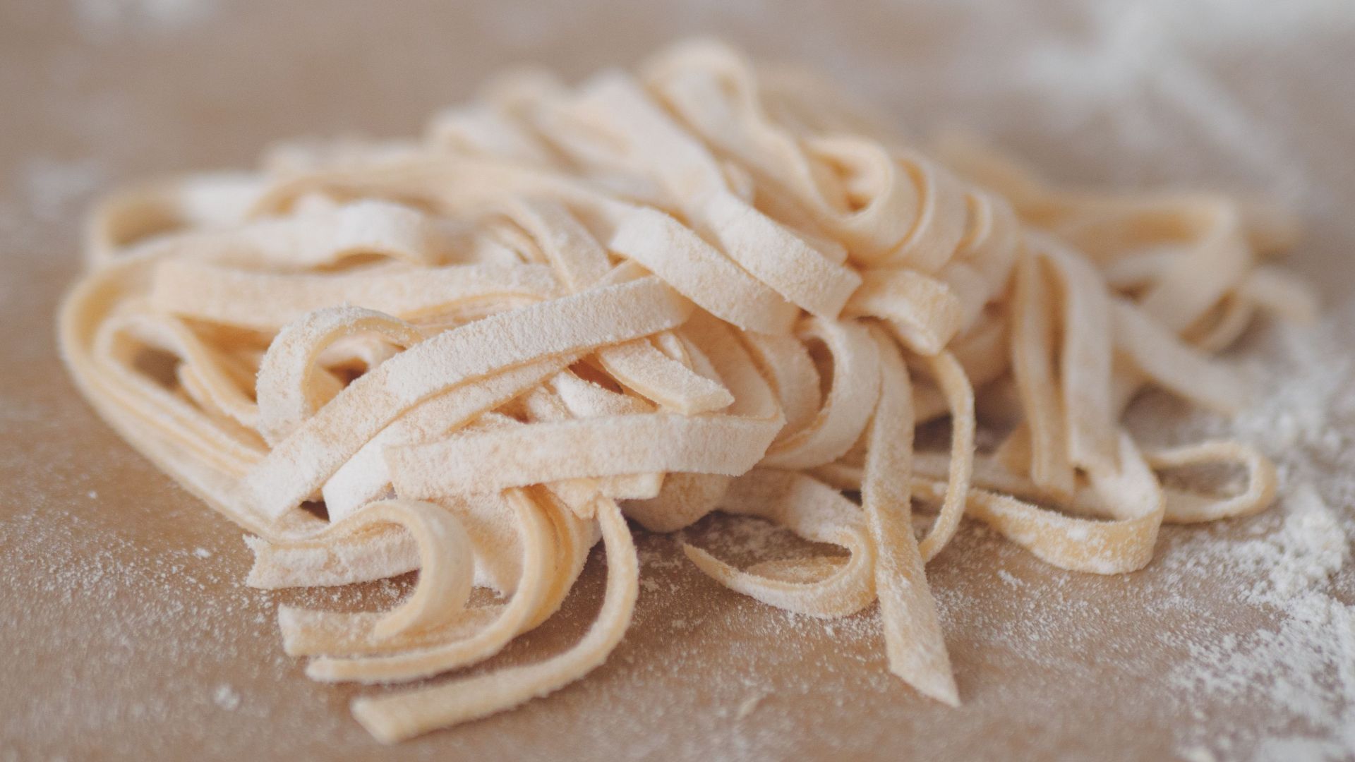Freshly prepared uncooked homemade pasta on a floured surface, ready for cooking.