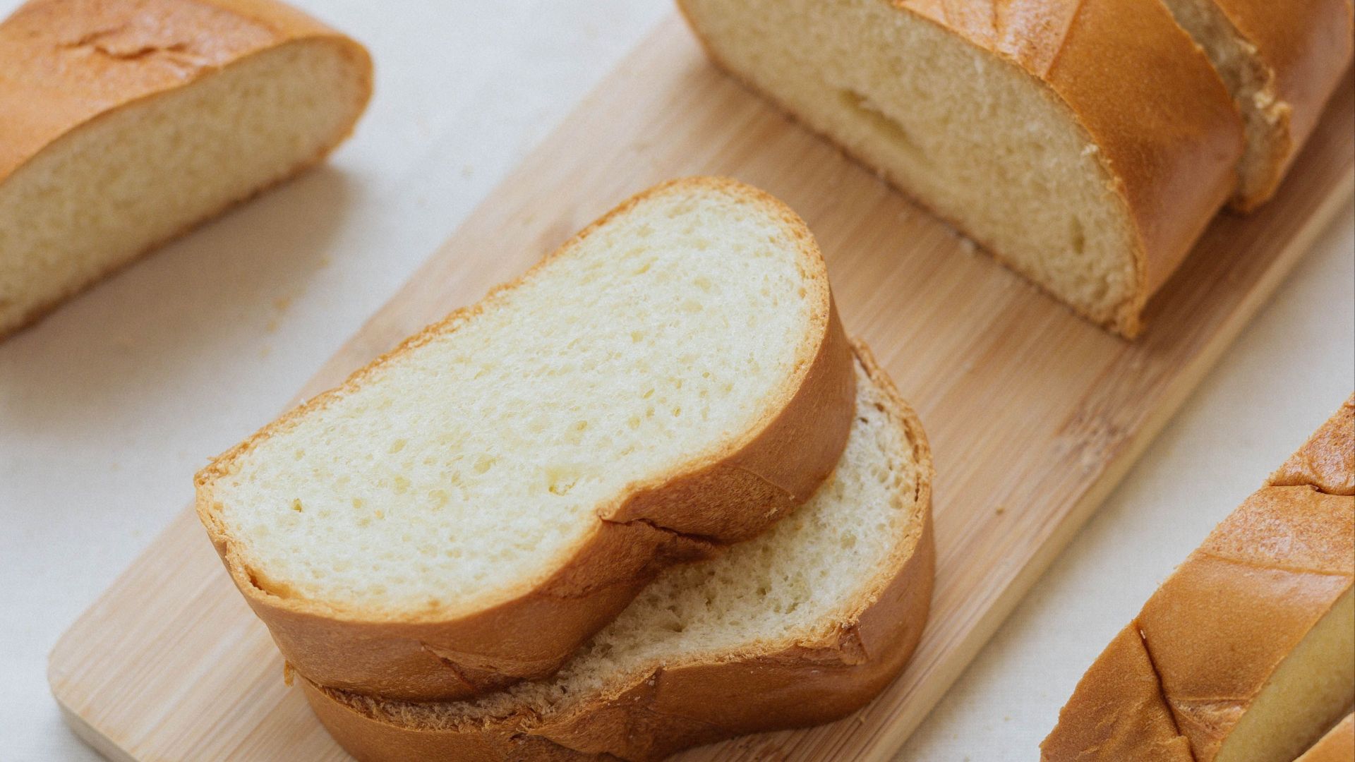 Sliced fresh bread on a wooden cutting board, perfect for breakfast or brunch spreads.