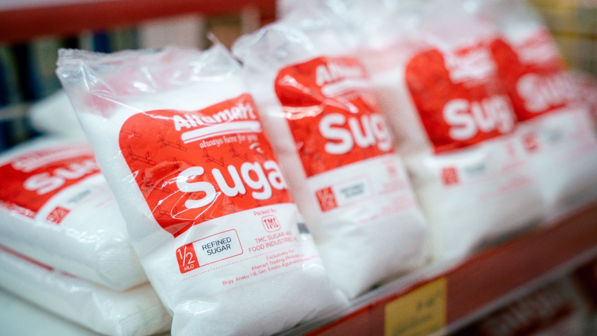 Close-up of sugar bags on a grocery store shelf, highlighting product packaging.