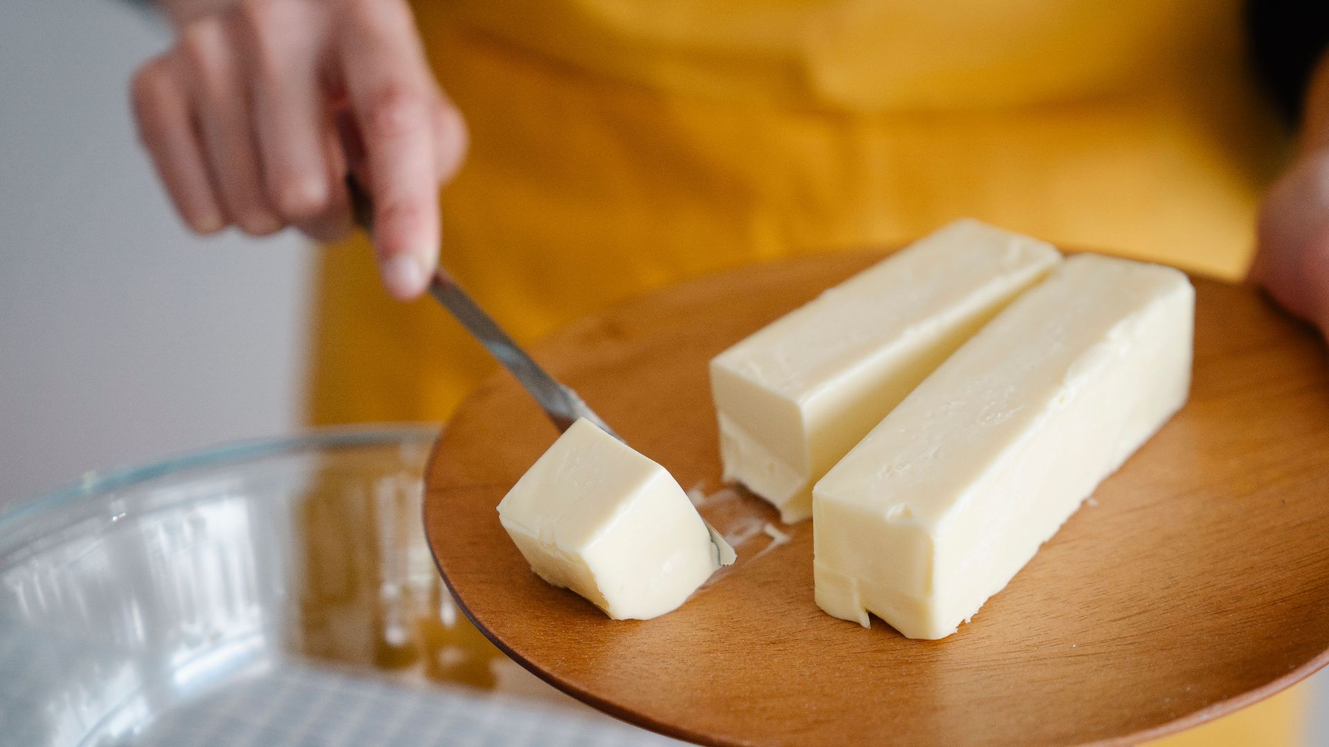 Focused shot of cutting butter for meal preparation, essential cooking ingredient.