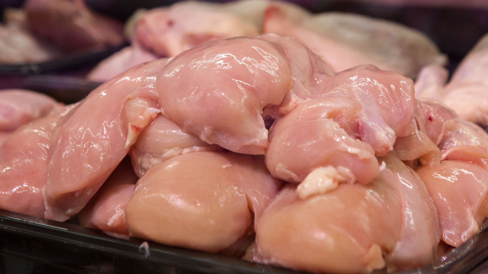 Fresh raw chicken breasts displayed in a supermarket setting, ready for purchase.