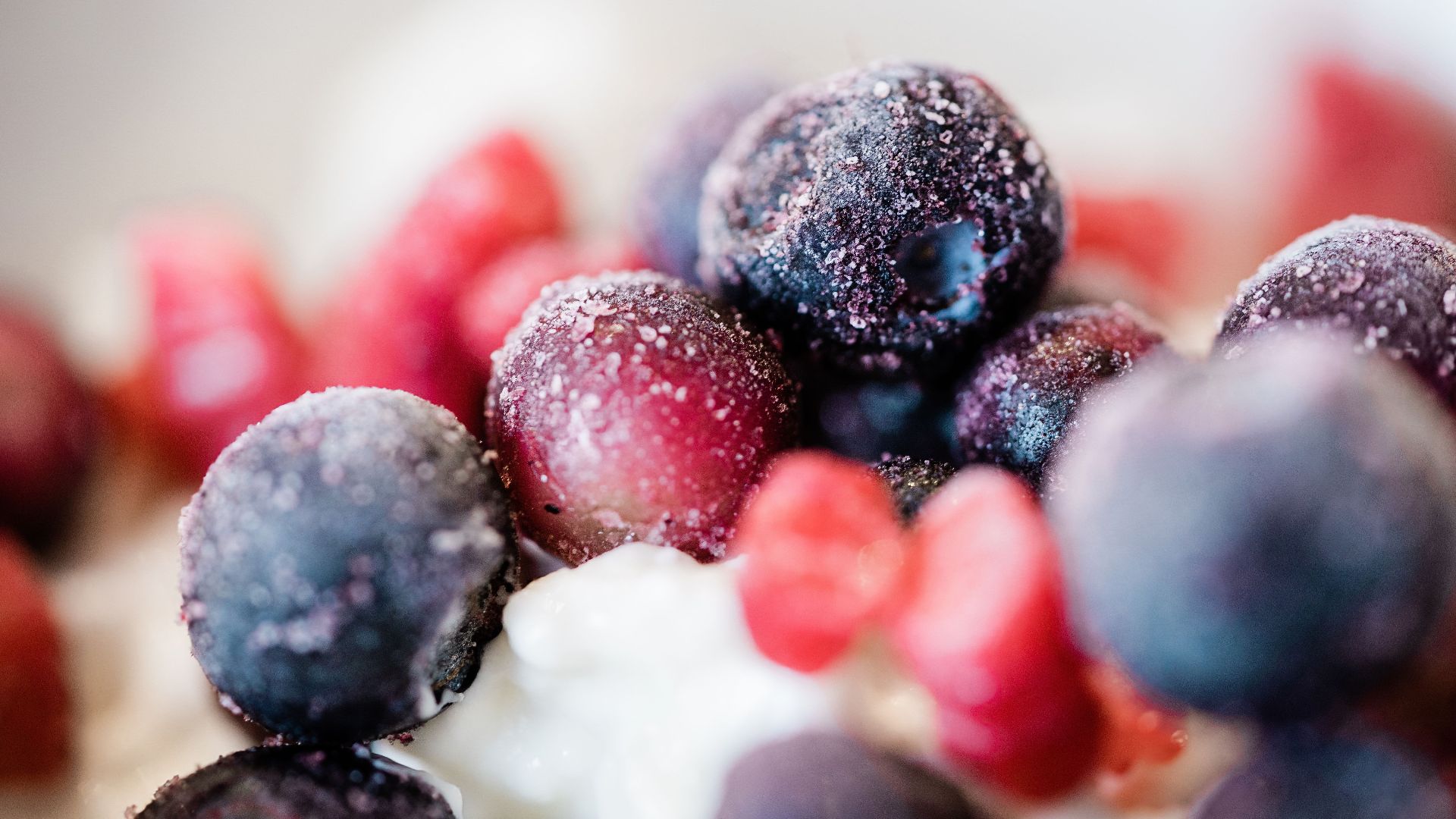 Delicious close-up of colorful frozen berries topped on a creamy dessert, perfect for food inspirations.