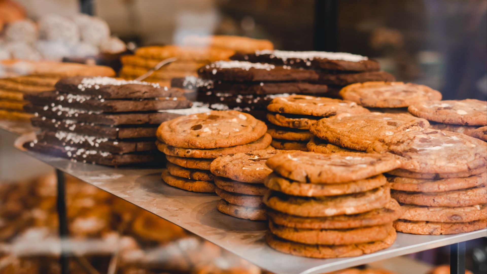 A variety of cookies neatly stacked on display in a bakery shop, showcasing gourmet pastries.